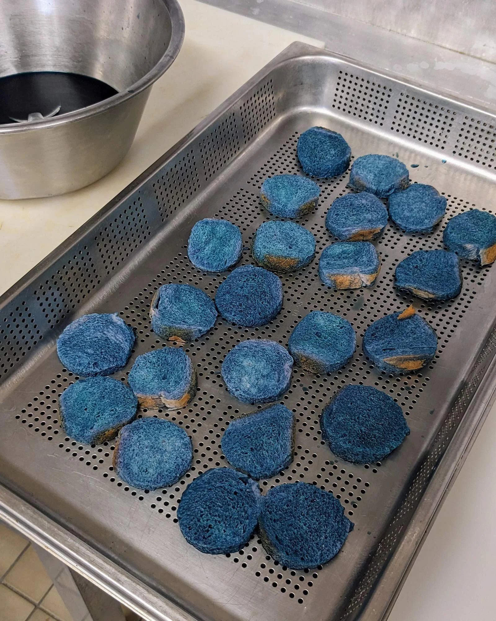 Tranches de pain de mie teintées naturellement en bleu, créant une esthétique singulière pour le banquet.