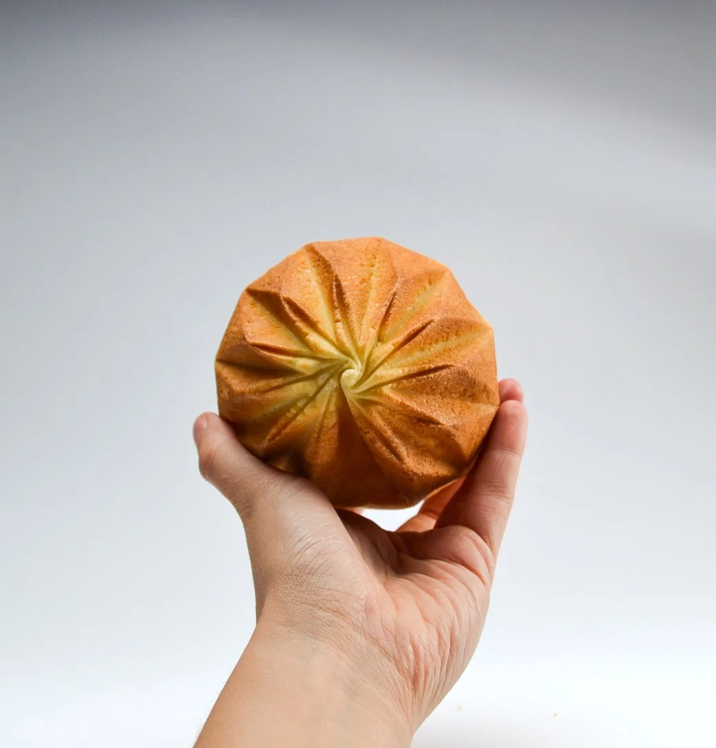 Brioche démoulée tenue en main montrant la géométrie de la cuisson.