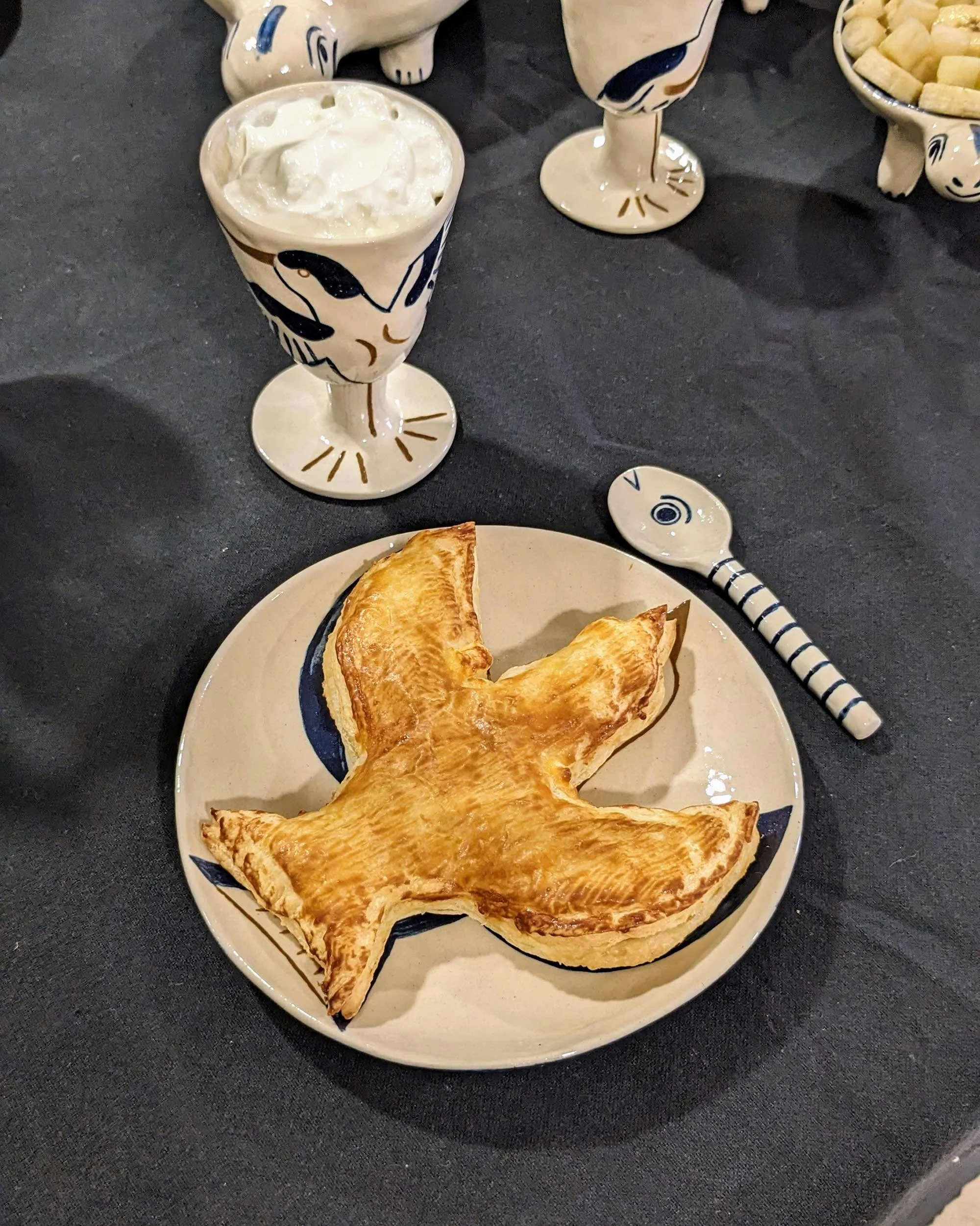Composition culinaire où un feuilleté en forme d'oiseau dialogue avec le dessin de l'assiette en céramique d'Amélie Fontaine.