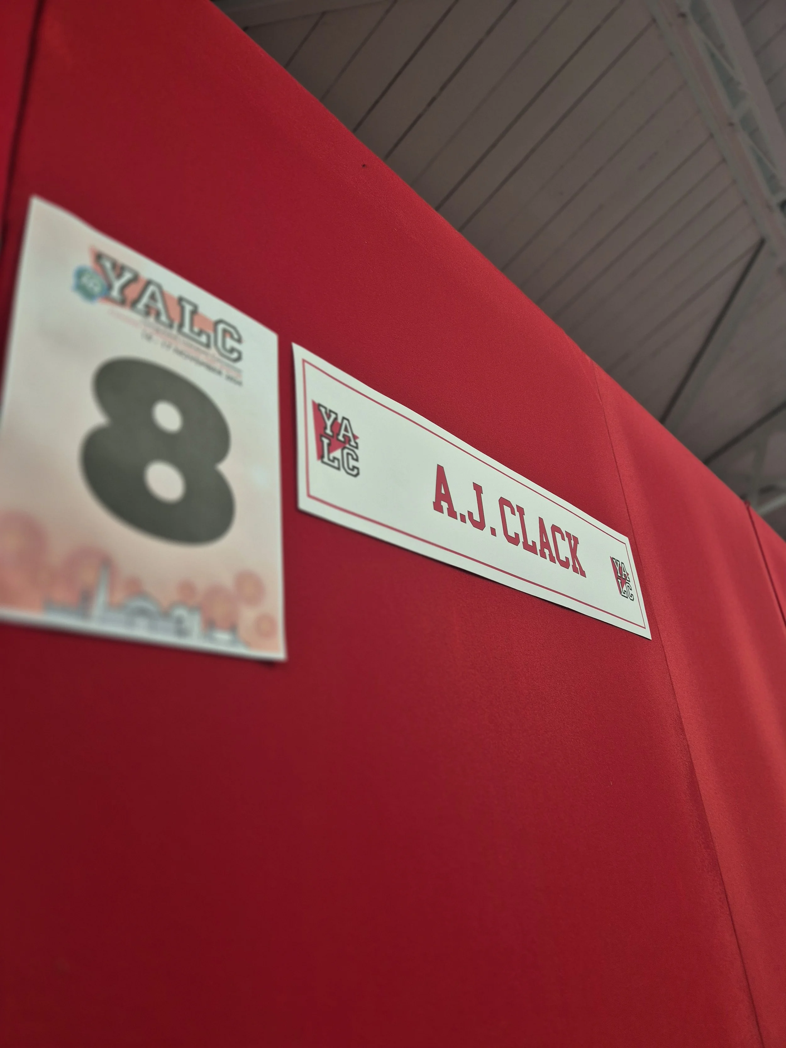 Red background with two signs: one showing the number 8 and the other with the name A.J. Clack