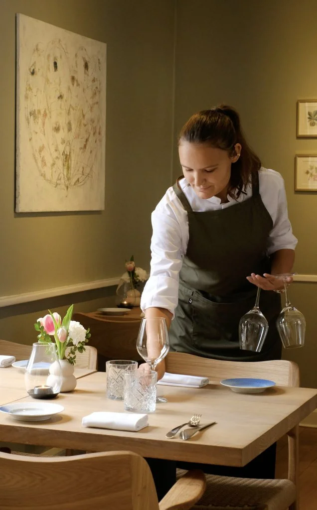 Tjener dækker bord på Den Røde Cottage.