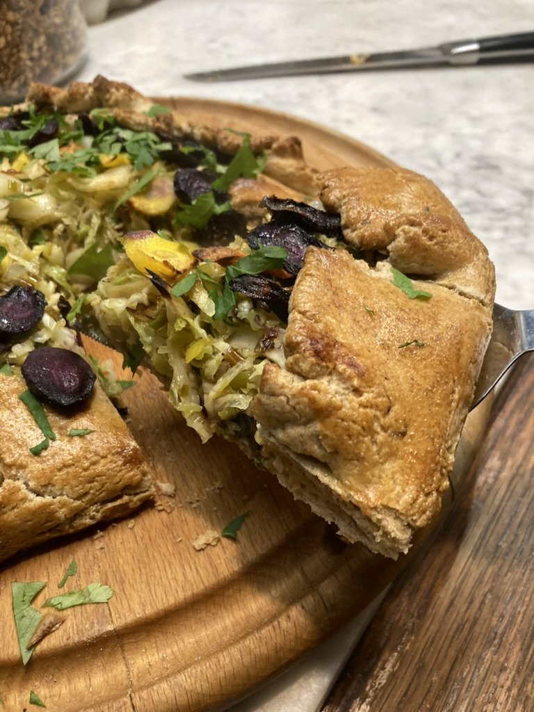 Groene en paarse salade met gefrituurde quiche gevuld met groenten, geserveerd op een houten snijplank.