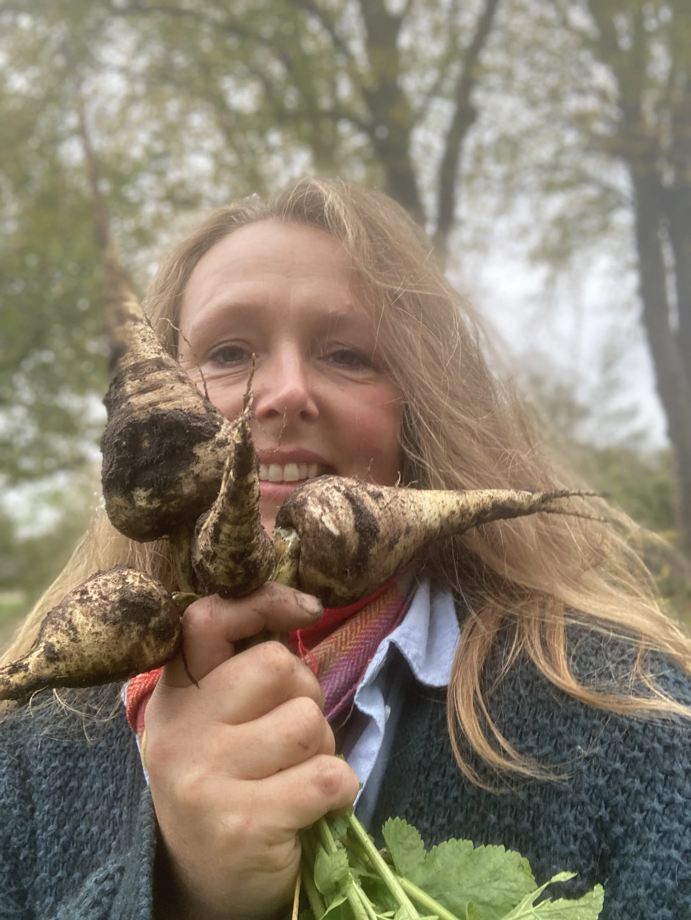 Vrouw die bosbessen met de hand vasthoudt, buitenshuis in een bosrijke omgeving, met glimlach.