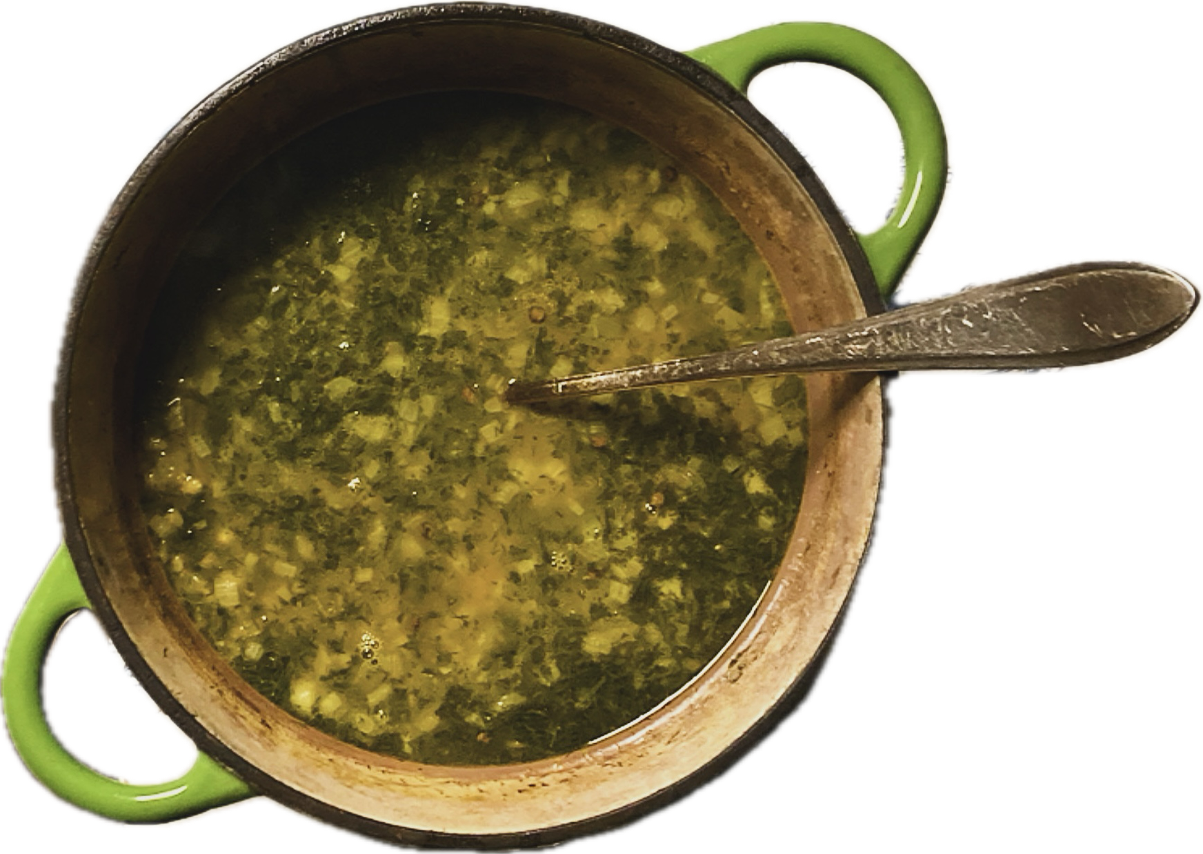 Een grote pot met groene soep en een lepel erin, afgietsels op de rand van de pot.