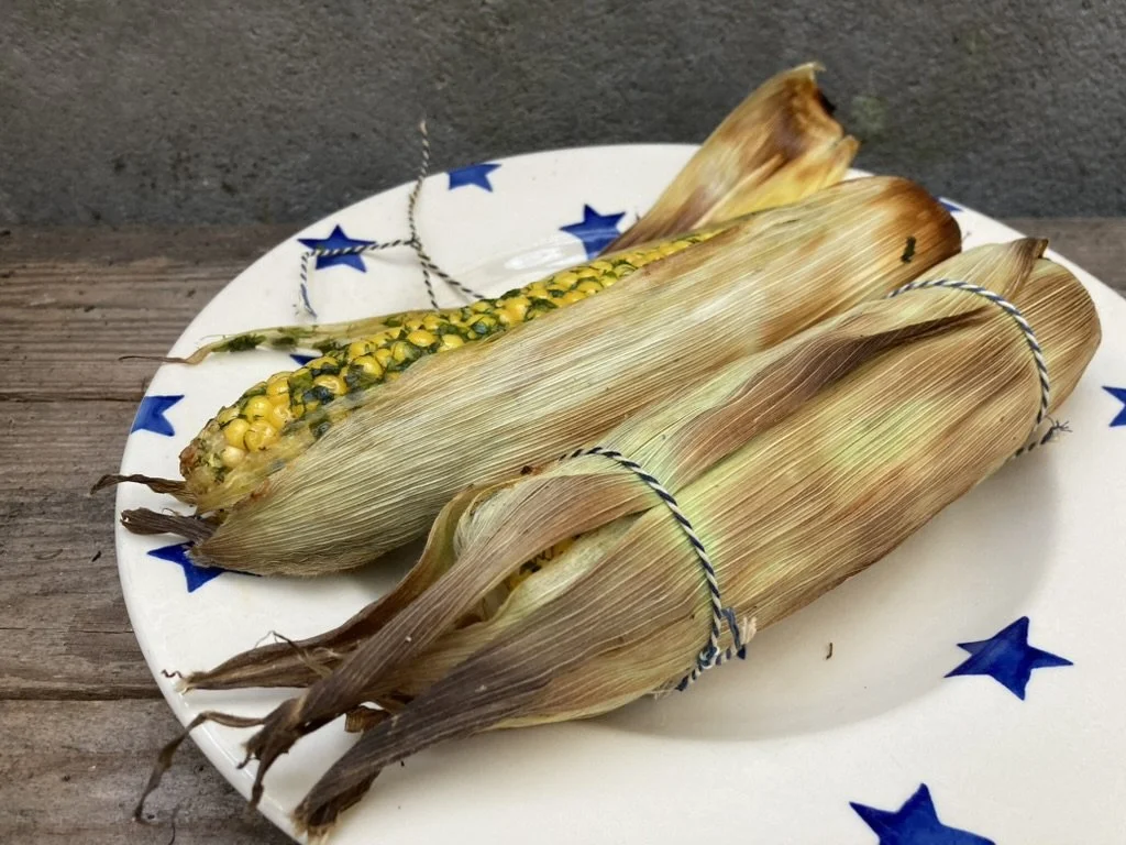 Drie kolven maïs op een white bord met blauwe sterren, op een houten tafel.