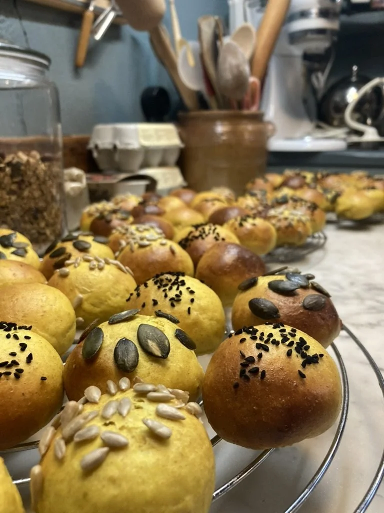 Versgebakken bolletjes met zaden en pitten, uitgestald op een rooster in een keuken.