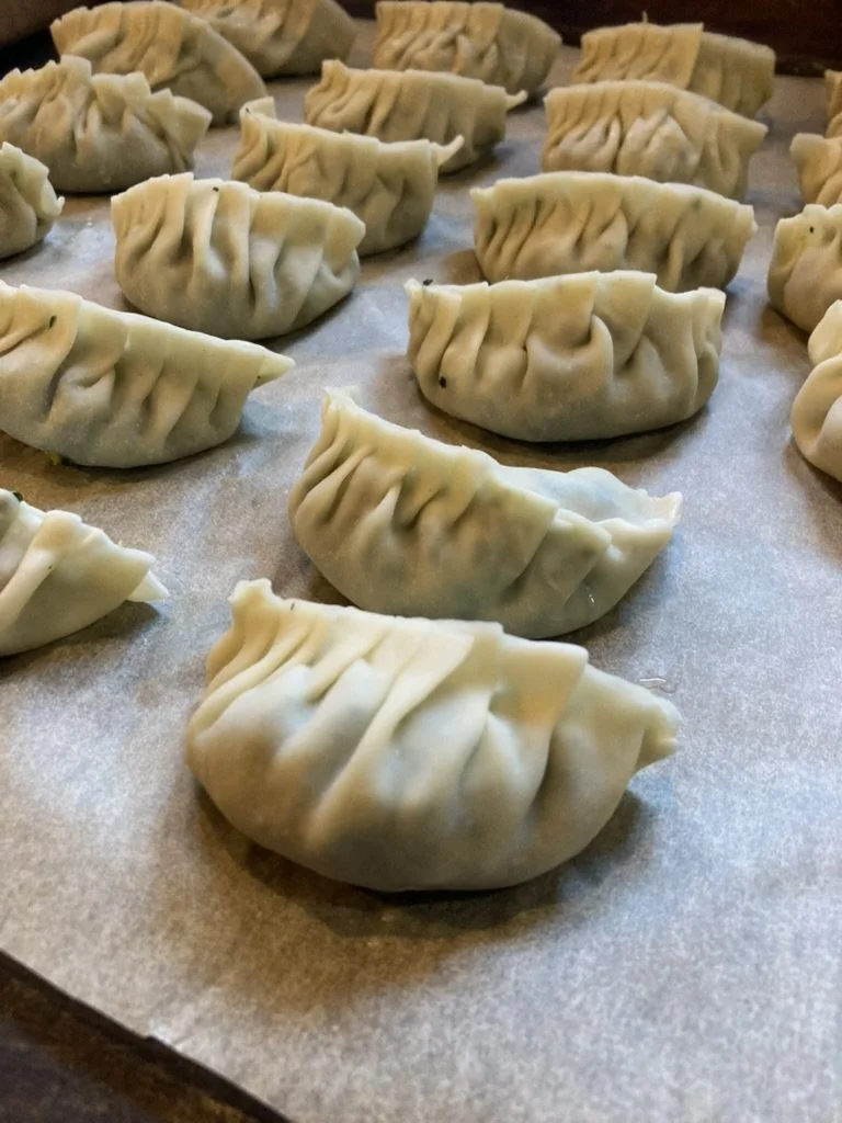 Ongekookte dumplings op een bakplaat.