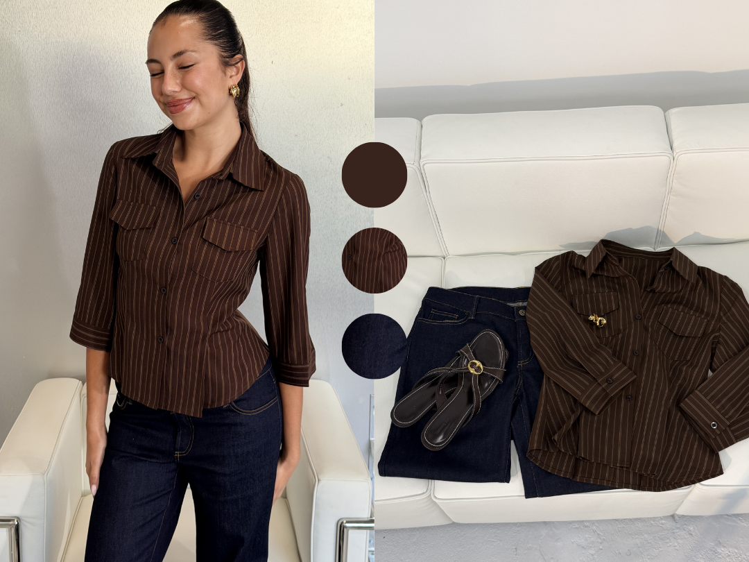 A woman wearing a brown pinstripe shirt with rolled-up sleeves and dark blue jeans, standing next to a white sofa. On the sofa, there is a matching brown pinstripe shirt, a pair of dark jeans, and black sandals.