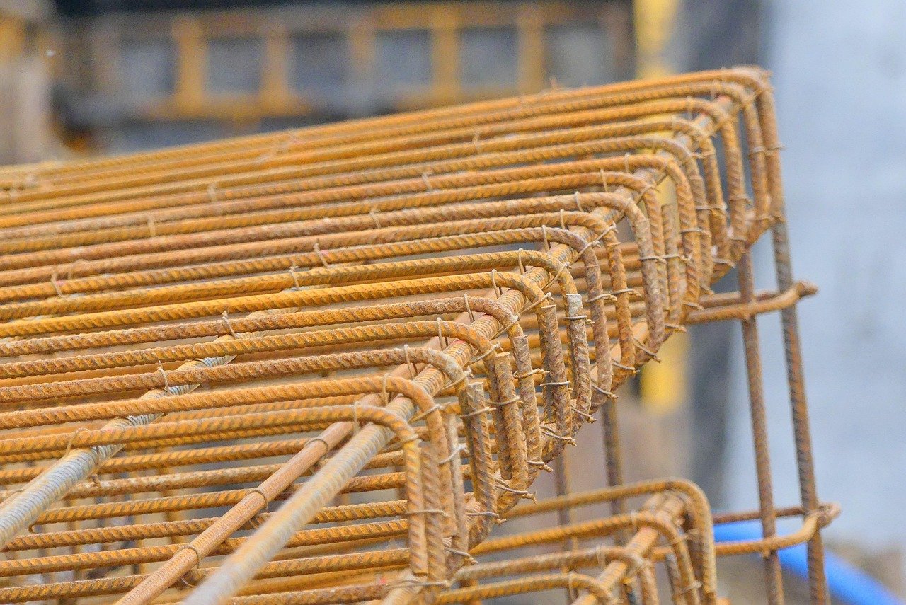 Rows of rusty metal rebar stacked outdoors for construction.