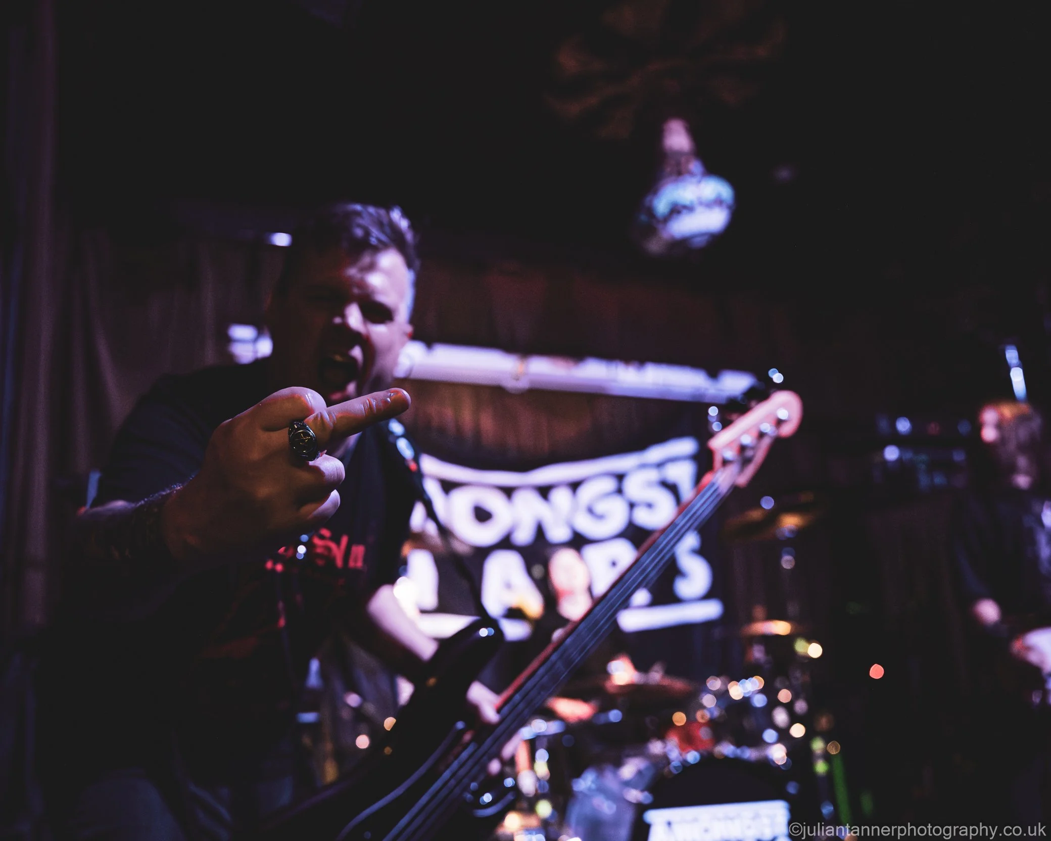 Elliot Blake, bass player in the hard rock band 'James Kennedy and The Underdogs' on stage waving his middle finger 