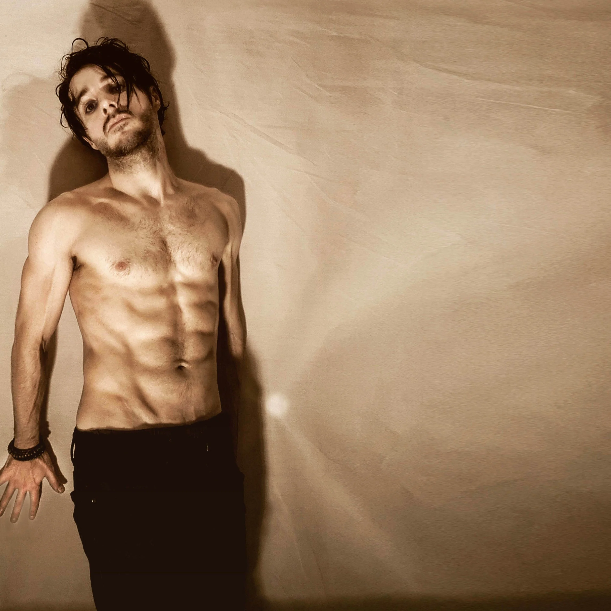 James Kennedy, the singer and musician in the band James Kennedy and The Underdogs posing shirtless with a long fringe 