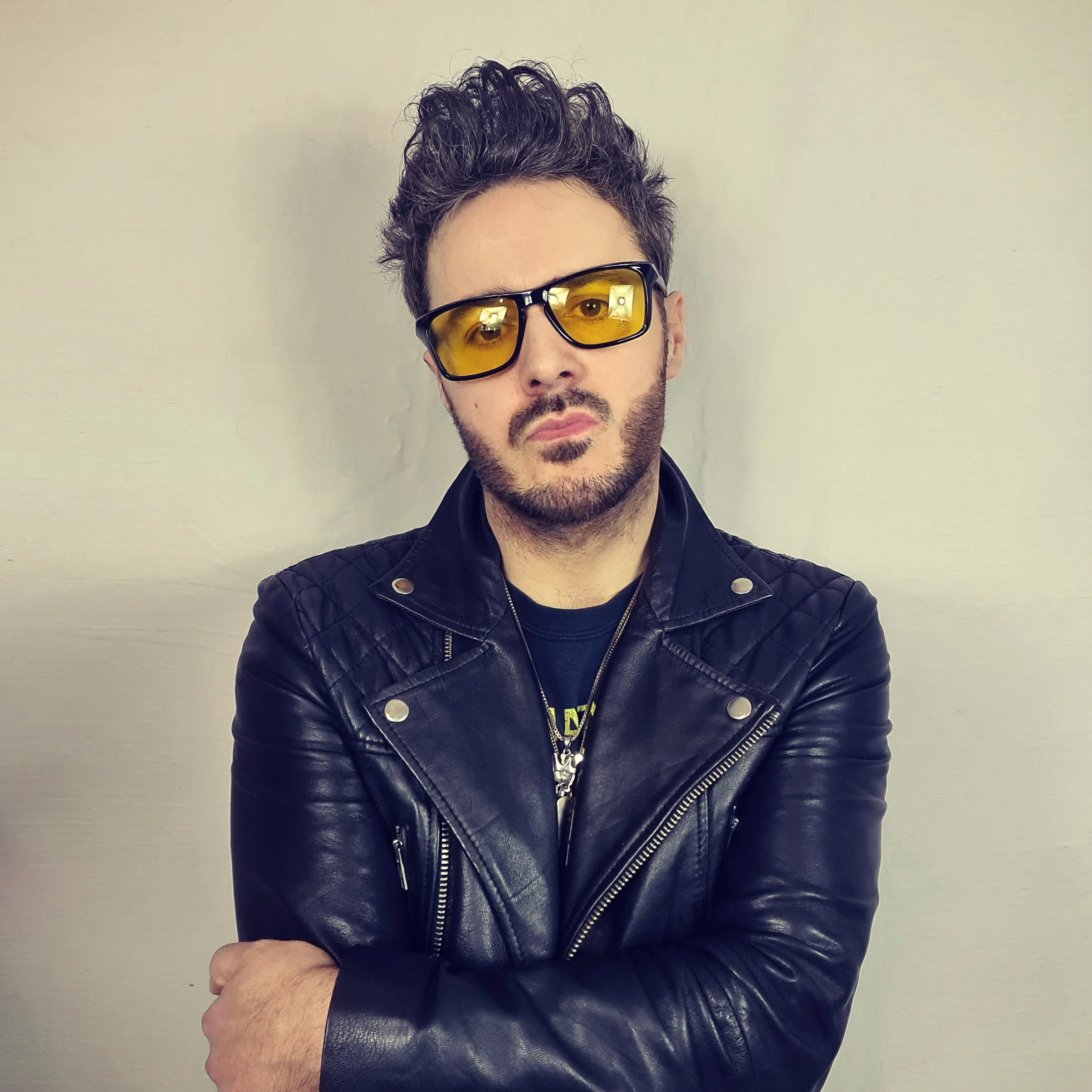James Kennedy, the singer, author, podcaster and frontman of the Underdogs and Kyshera bands posing arms folded in a leather jacket and tinted glasses