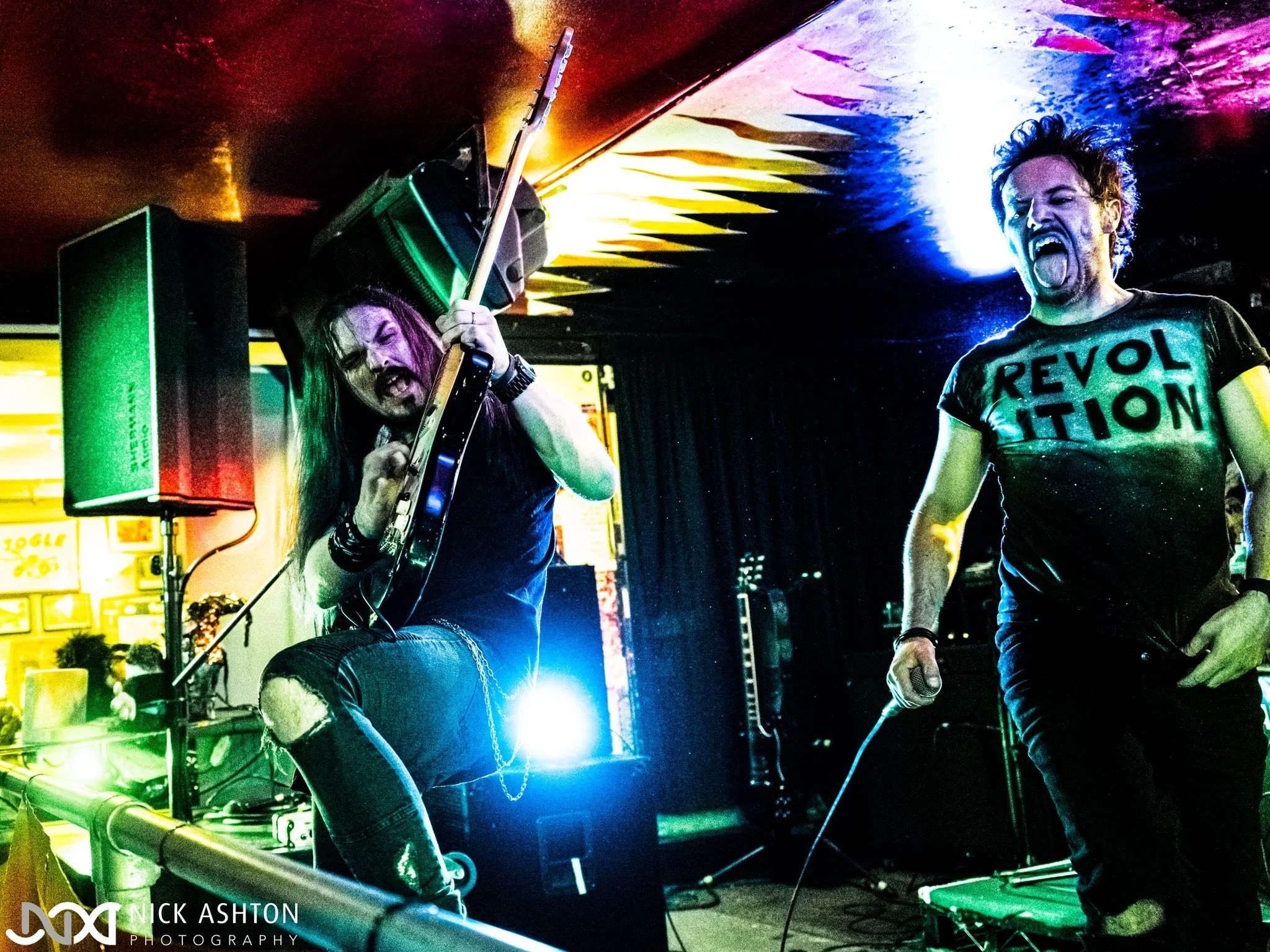 Jack Davies and James Kennedy of the rock band 'James Kennedy and The Underdogs' poking their tongues out on stage at a concert 