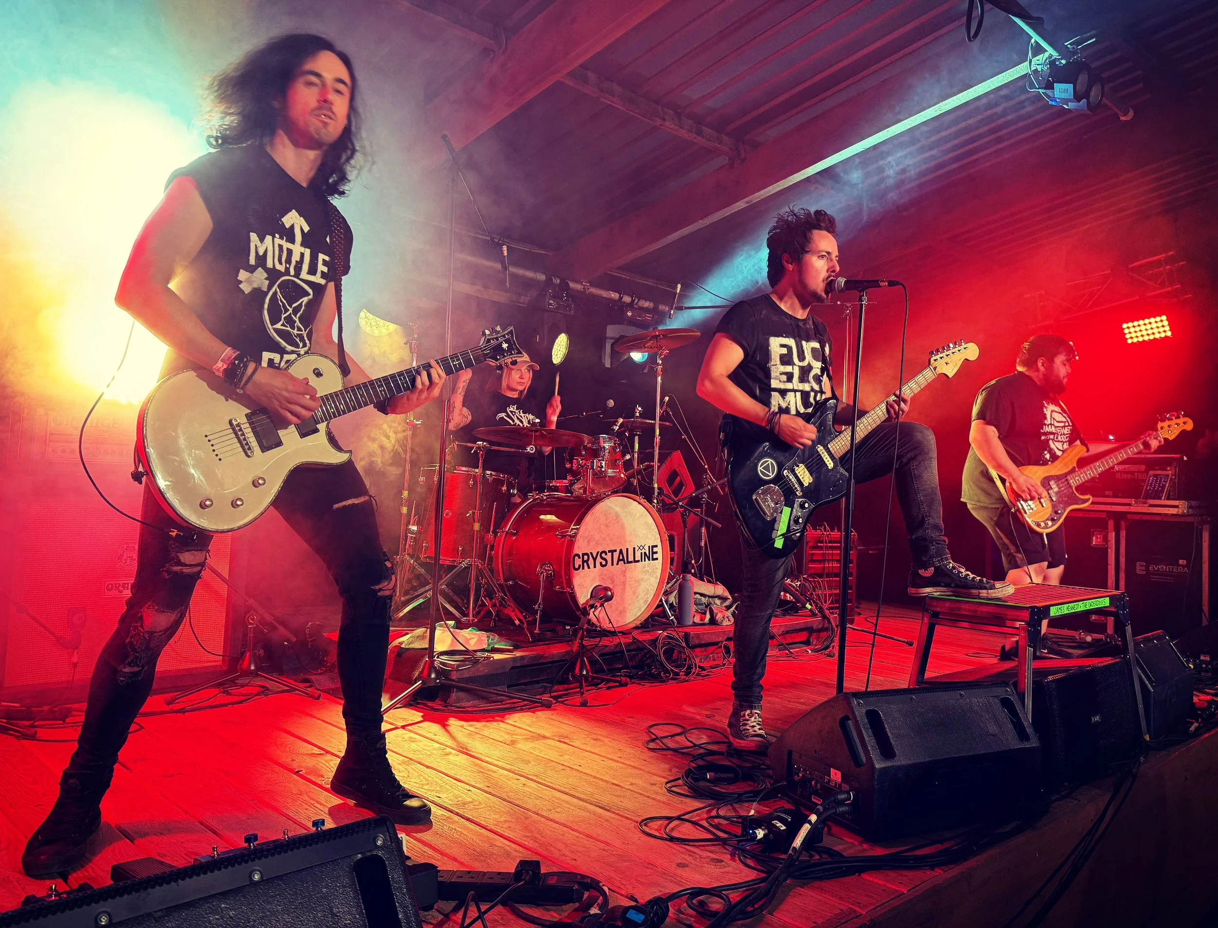 Welsh punk rock band 'James Kennedy and The Underdogs' playing a concert at Down On The Farm festival in Wales 2025 with red stage lights. Singer James Kennedy has his foot on the stage monitor 