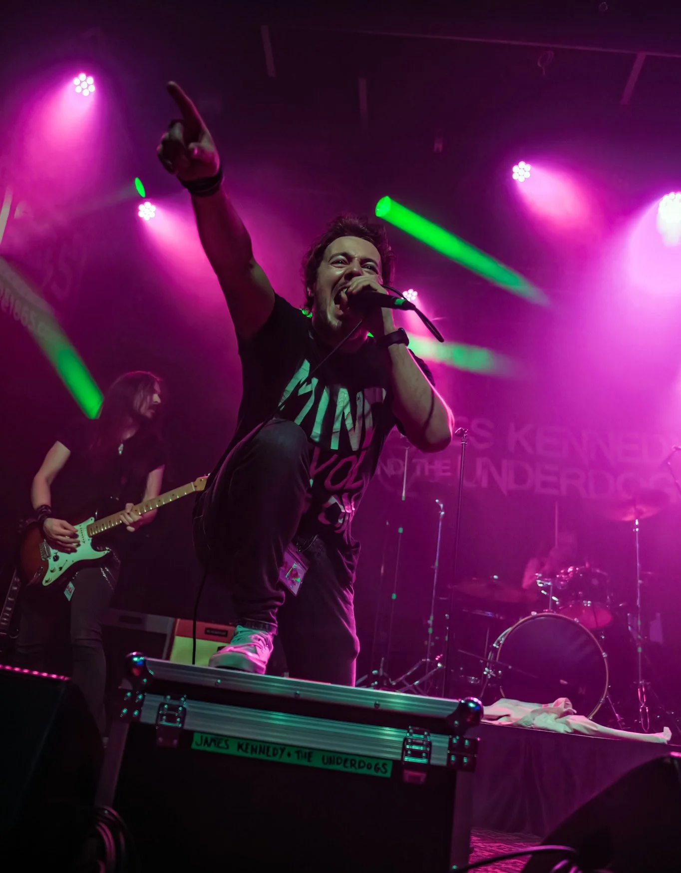 James Kennedy, singer of the band 'James Kennedy and The Underdogs' on stage at Nozfest 2025 with his hand in the air under pink stage lights 