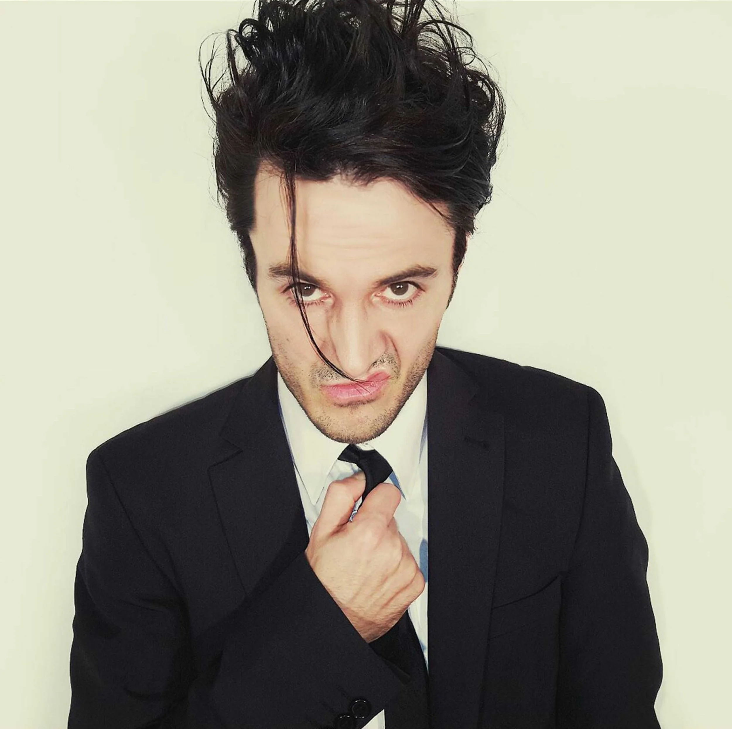 James Kennedy, the singer and frontman of the rock bands 'Kyshera' and 'James Kennedy and The Underdogs' wearing a suit and snarling with a long fringe