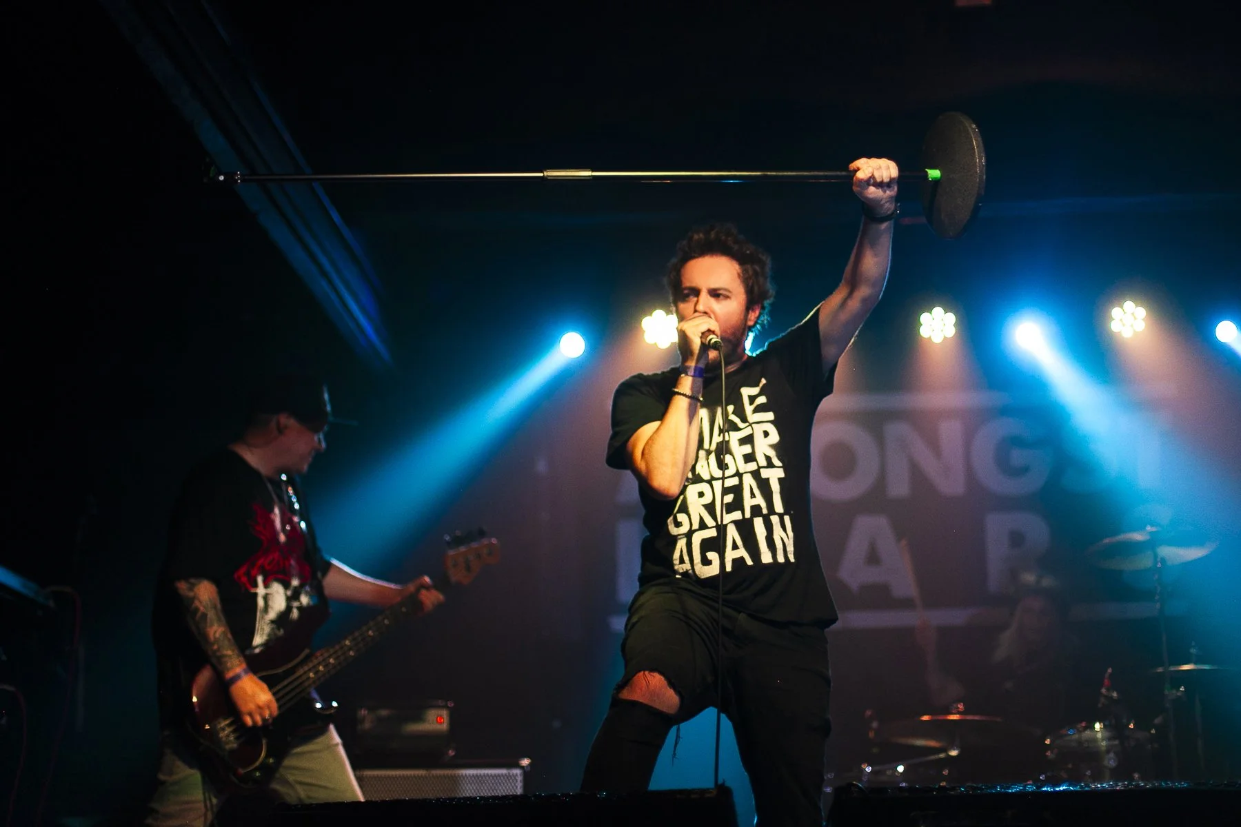 Welsh singer James Kennedy performing on stage with his band 'James Kennedy and The Underdogs' and holding a microphone stand in the air