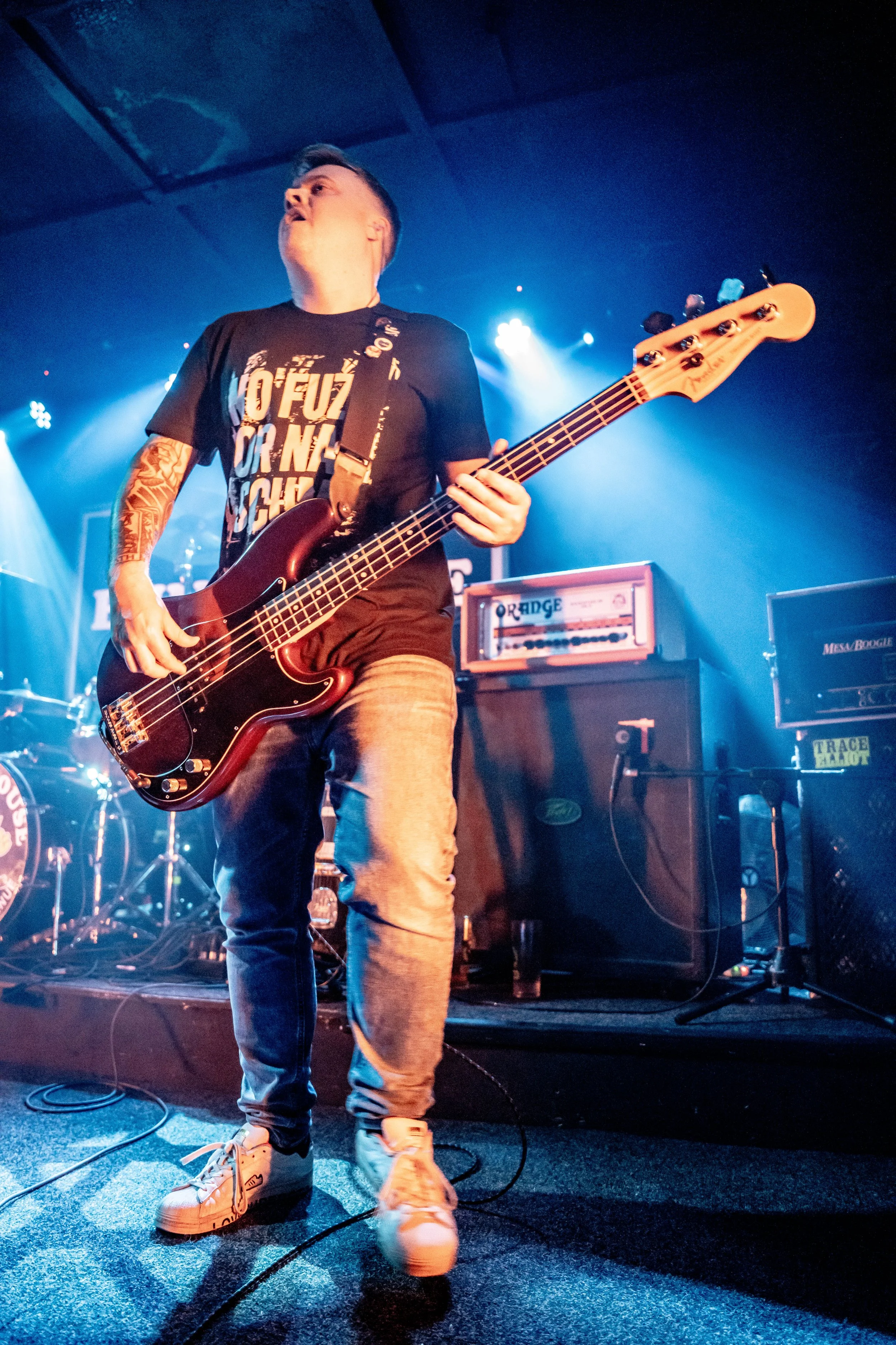 Elliot Blake, bass player with the Welsh rock band 'James Kennedy and The Underdogs' on stage under blue stage lights 