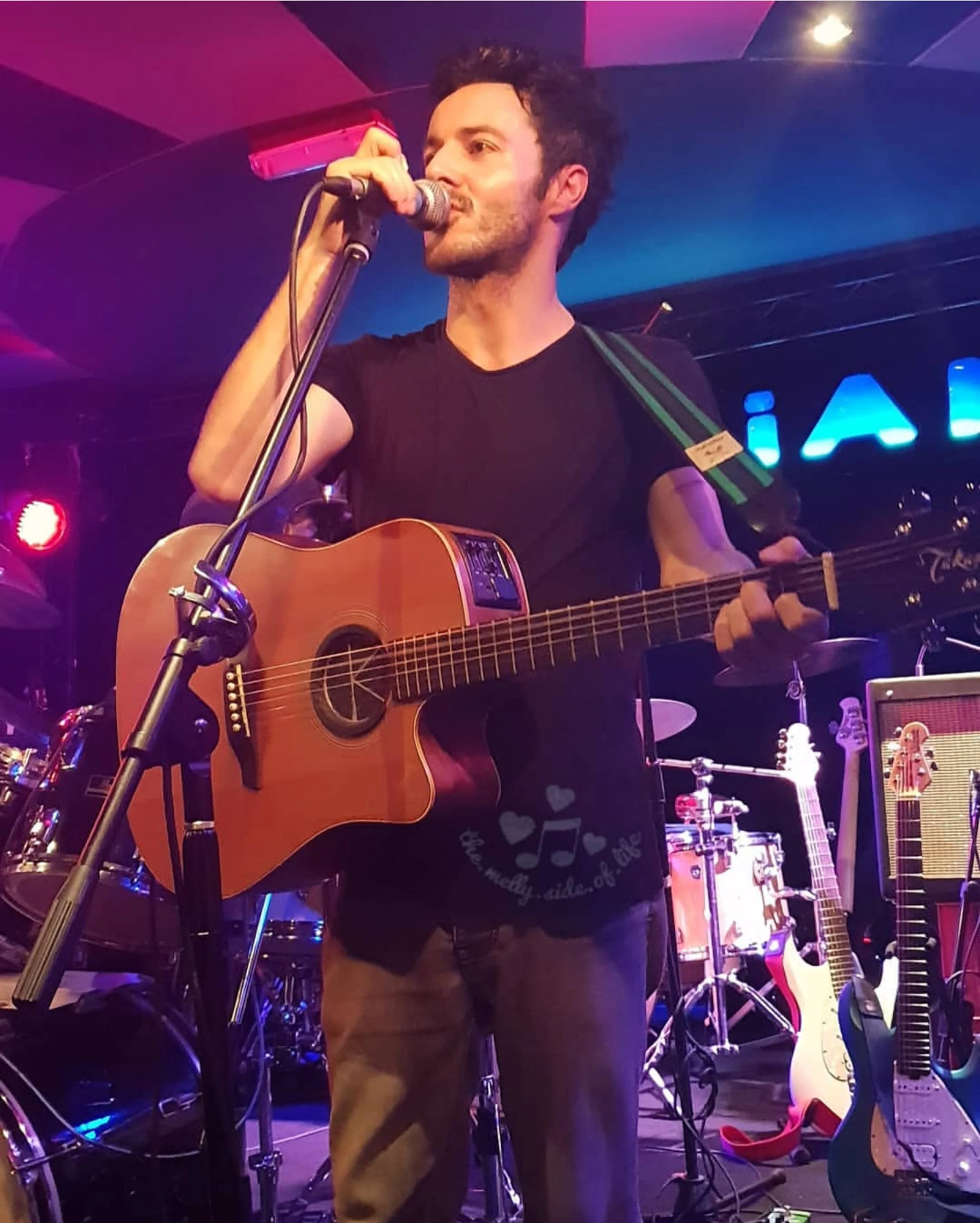 James Kennedy, the singer songwriter from Wales playing an acoustic guitar at a solo concert 