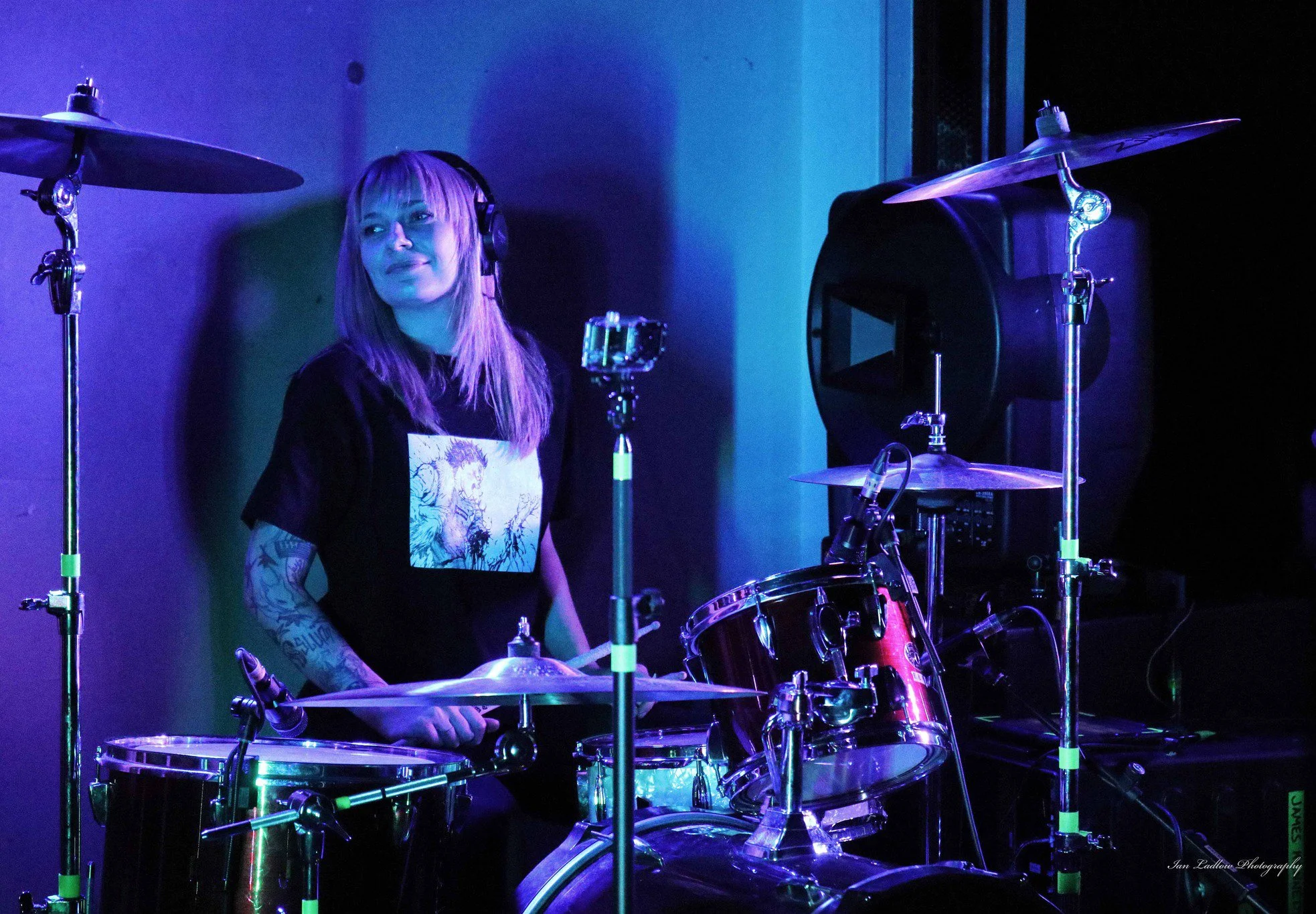 Aggy Nowicka, the drummer in the band 'James Kennedy and The Underdogs' sitting behind her drum set on stage during a concert and smiling 