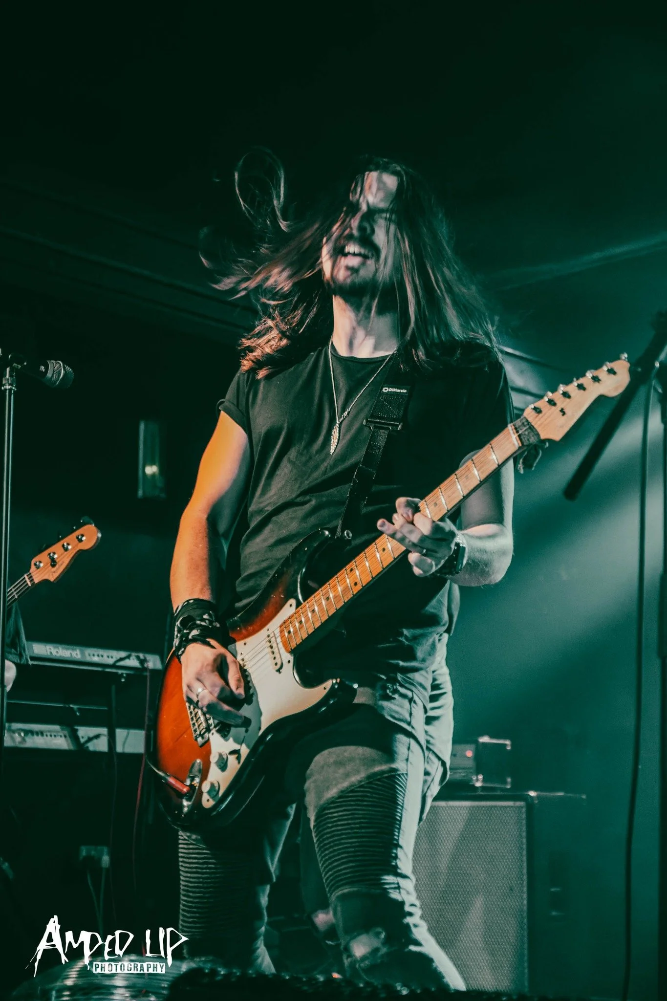 Jack Davies, the guitar player in the Welsh punk rock band 'James Kennedy and The Underdogs' playing his Fender Strat guitar on stage and waving his long hair 