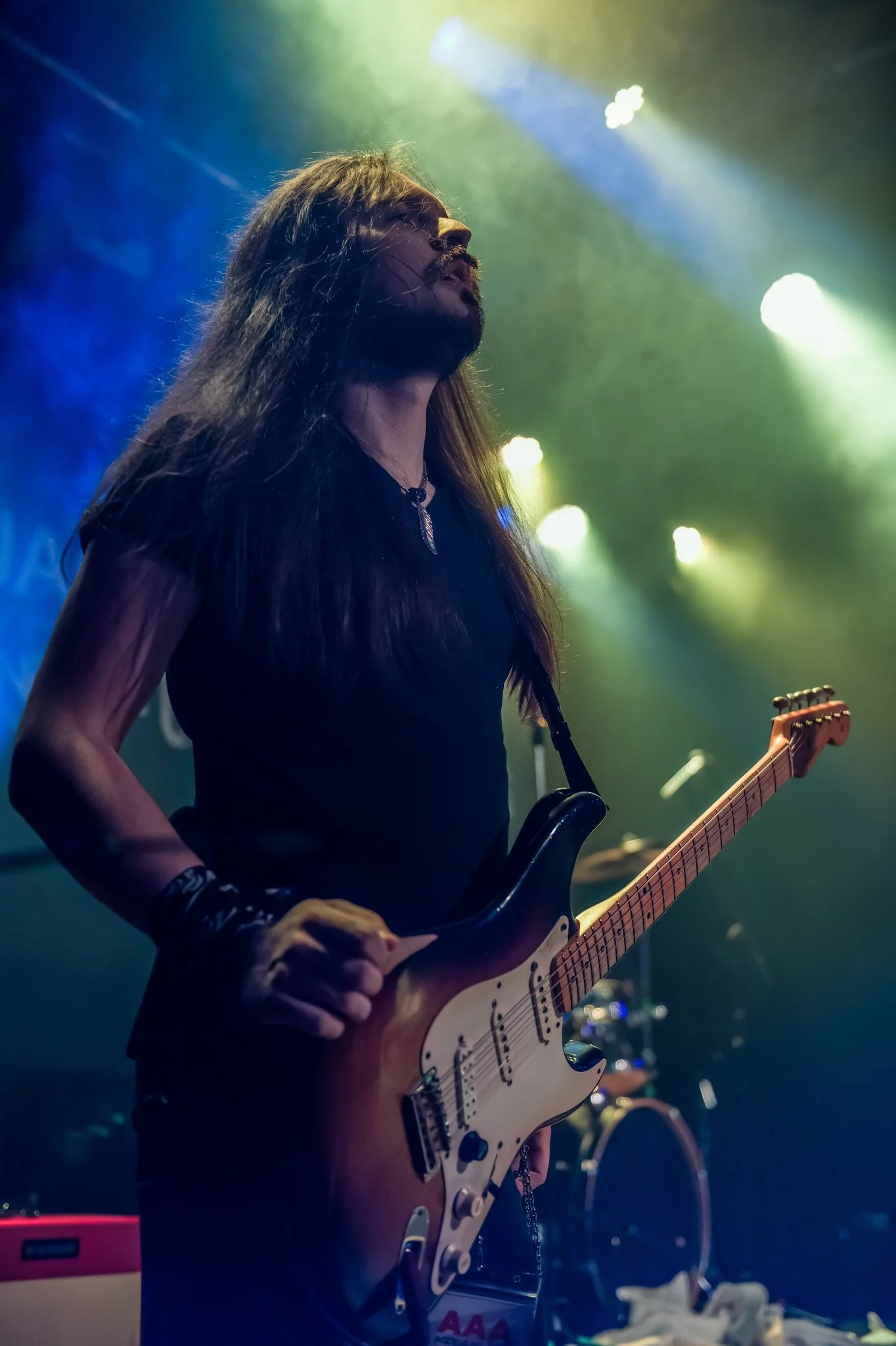 Jack Davies, guitarist with the rock band 'James Kennedy and The Underdogs' on stage, holding his Fender Stratocaster under stage lights 