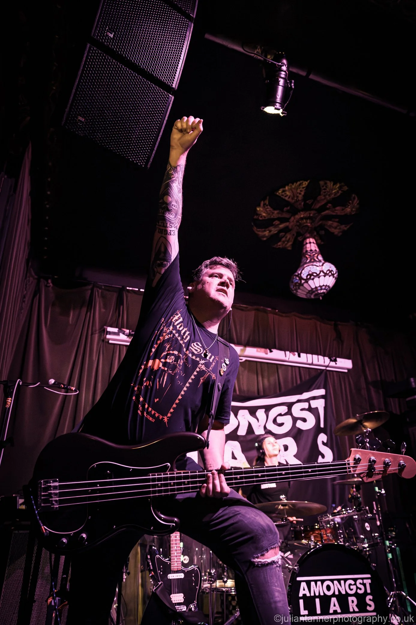Elliot Blake, the bass player in the Welsh punk rock band 'James Kennedy and The Underdogs' holding his fist in the air on stage during a concert 