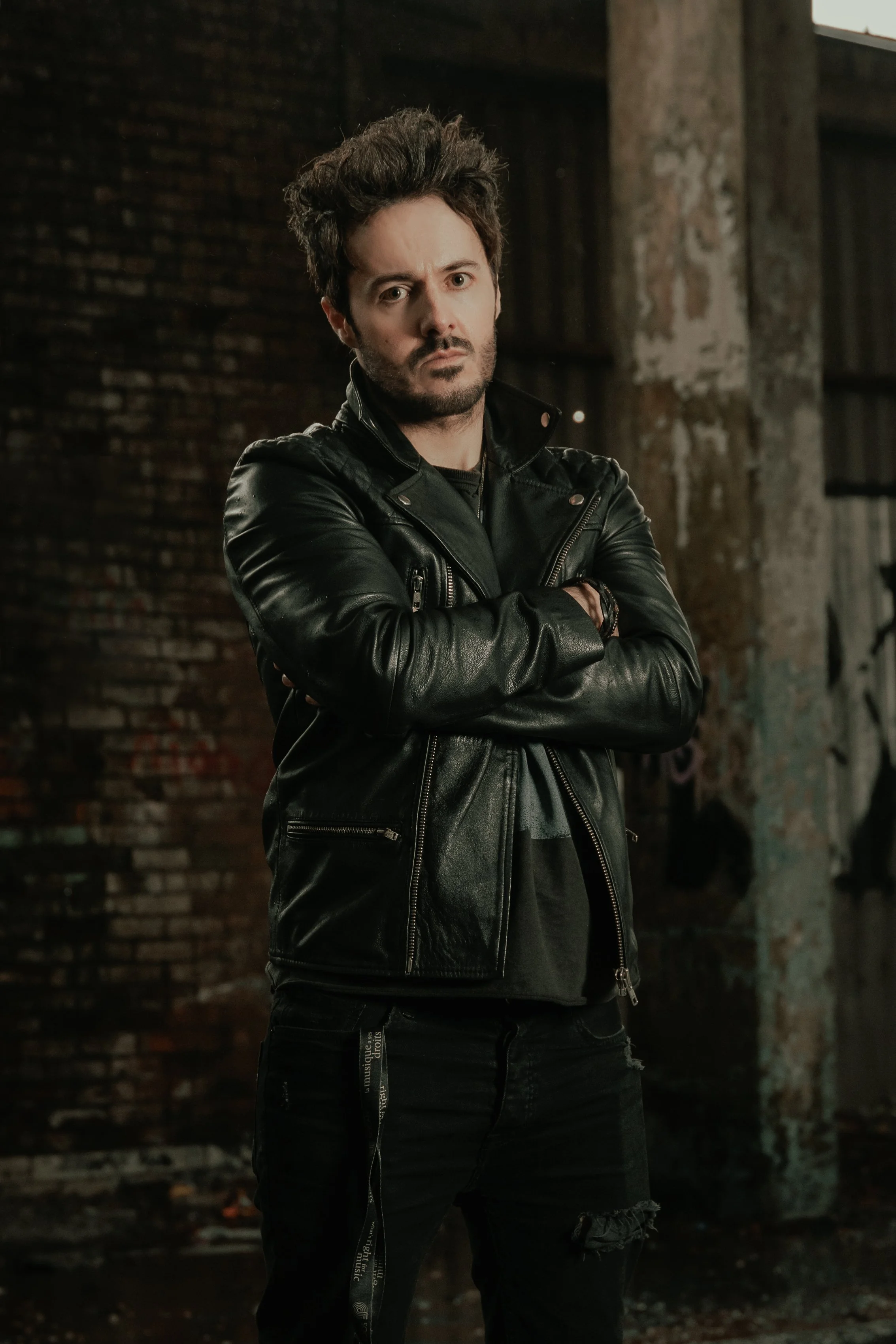 James Kennedy, singer in the rock band 'James Kennedy and The Underdogs' posing with his arms crossed in a leather jacket with spike hair