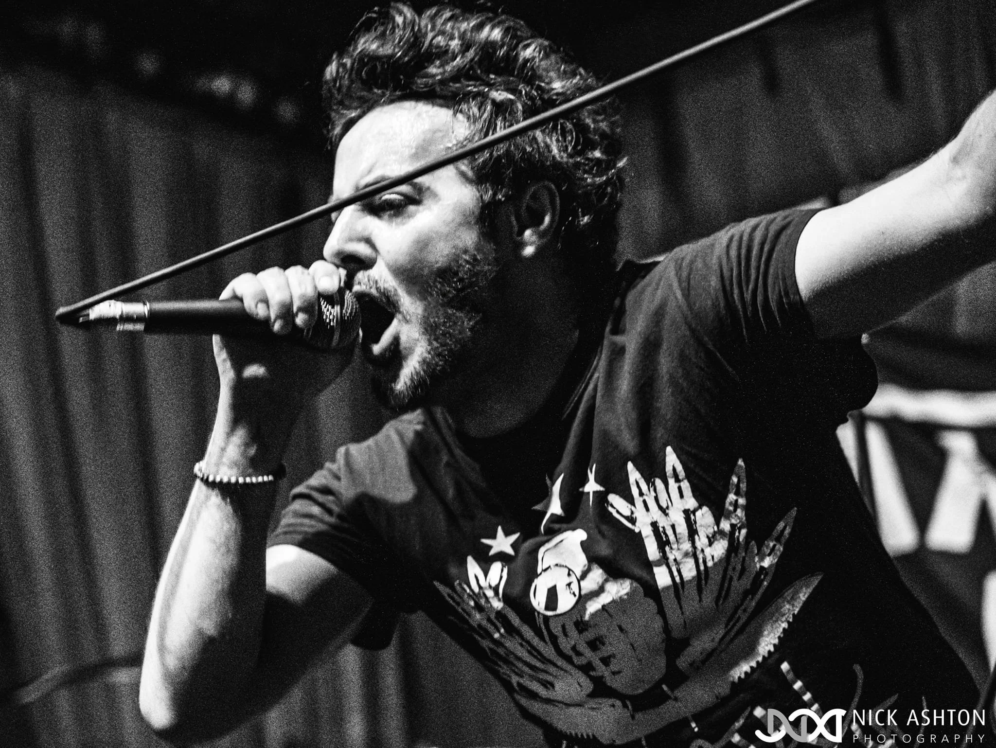 James Kennedy, the singer in the band 'James Kennedy and The Underdogs' singing into the microphone during a concert and pulling the microphone cable with his other hand