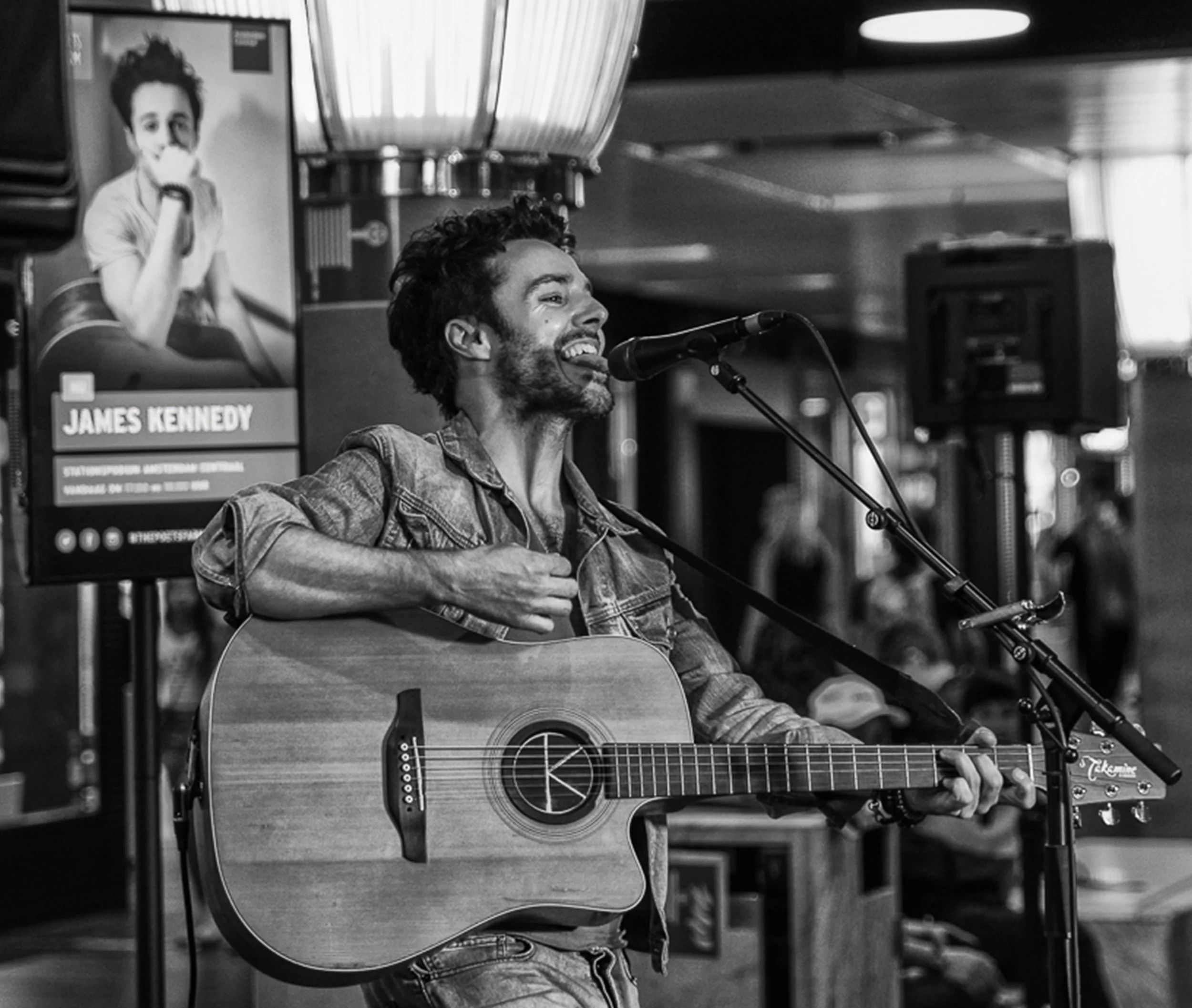 James Kennedy, the singer and musician playing an acoustic guitar at a solo concert in Amsterdam