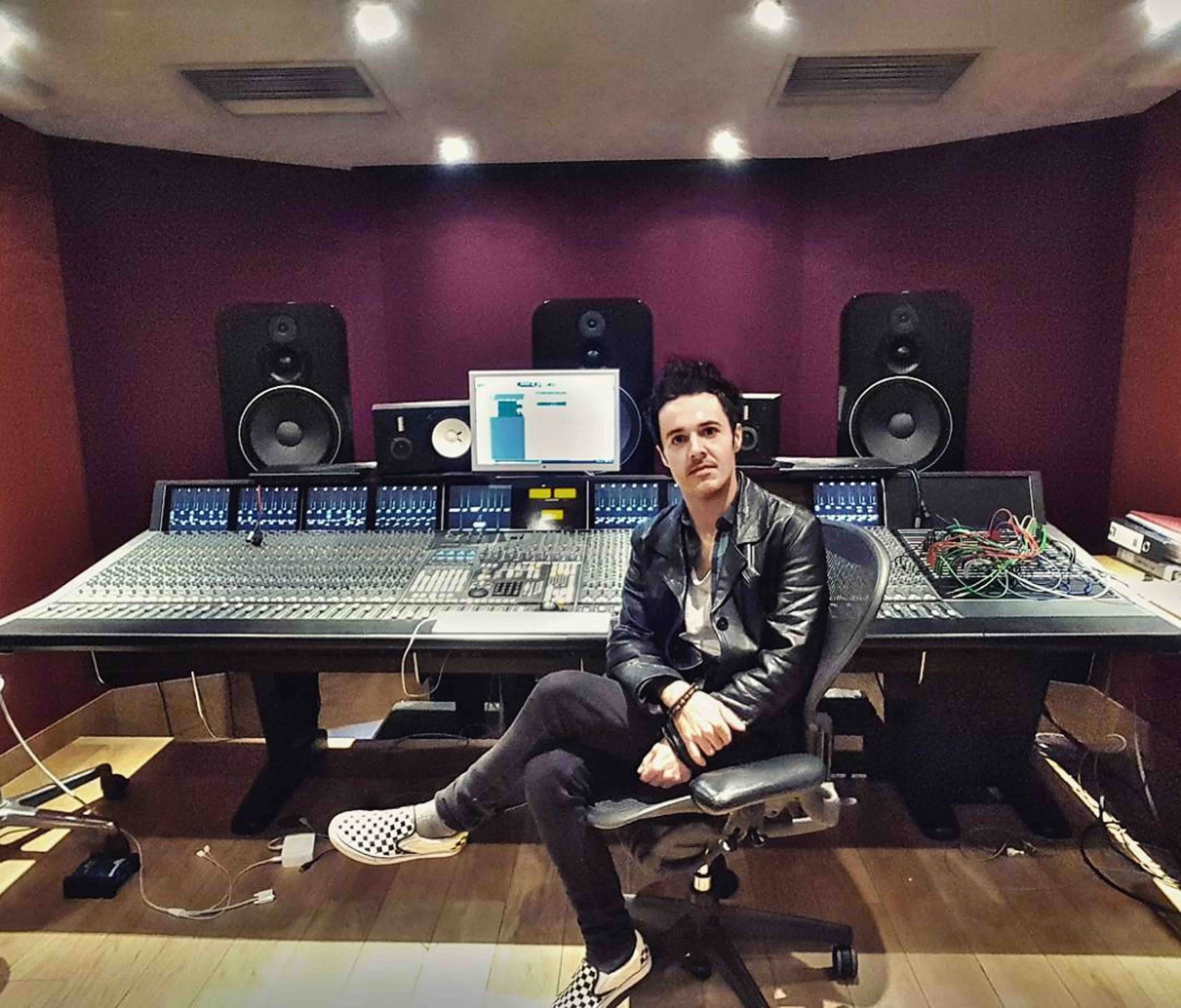 James Kennedy, the singer, author and podcaster sat in front of a large studio mixing console in a recording studio 