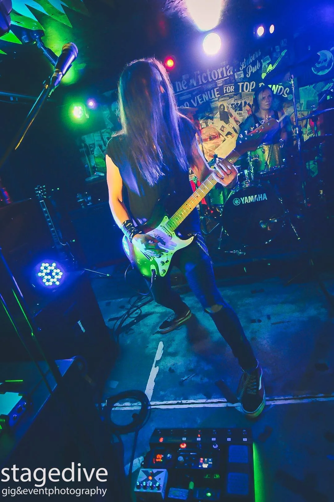 Jack Davies, guitarist with the rock band 'James Kennedy and The Underdogs' live on stage playing his guitar with his hair in his face