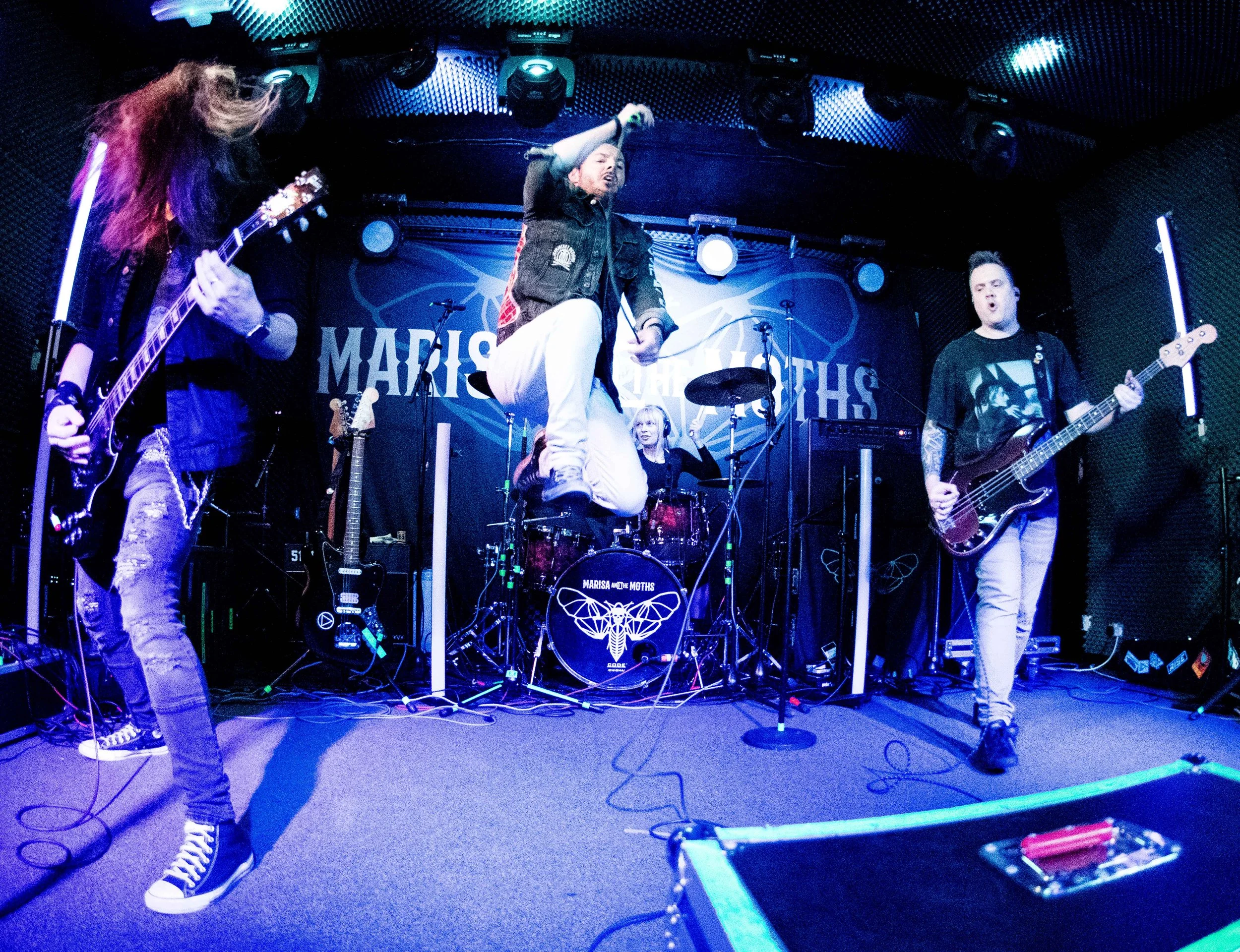 The 'James Kennedy and the Underdogs' band on stage on tour with singer, James Kennedy jumping in the air