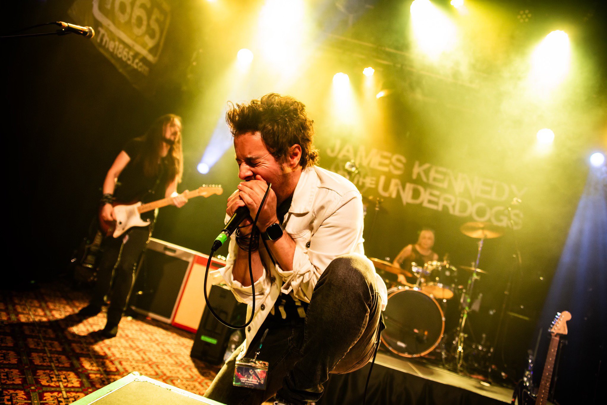 'James Kennedy and the Underdogs' on stage at Nozfest 2025 with singer, James Kennedy screaming into the microphone under yellow stage lights