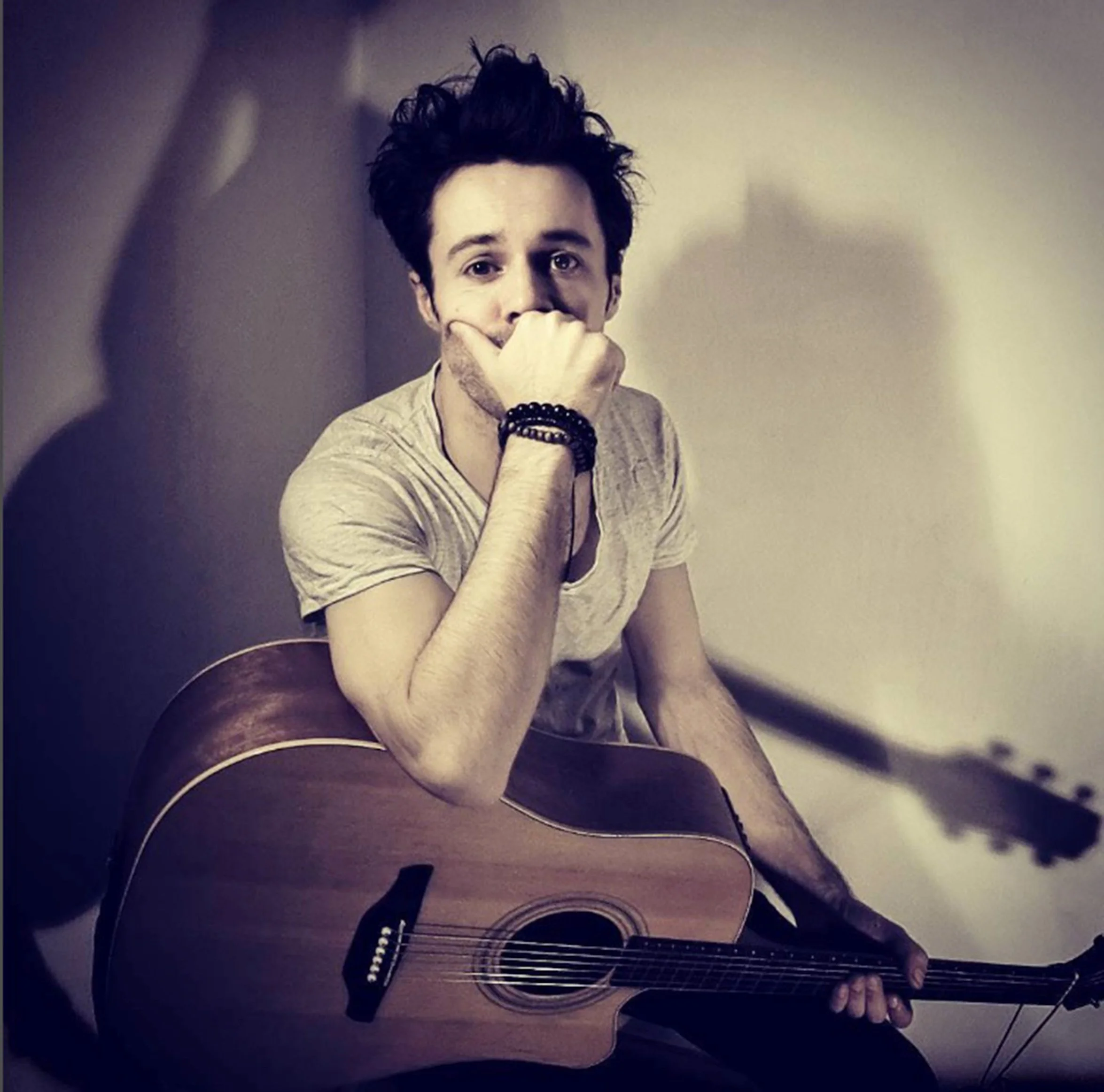 James Kennedy, the singer and frontman of the rock band 'James Kennedy and The Underdogs' posing with an acoustic guitar and messy hair