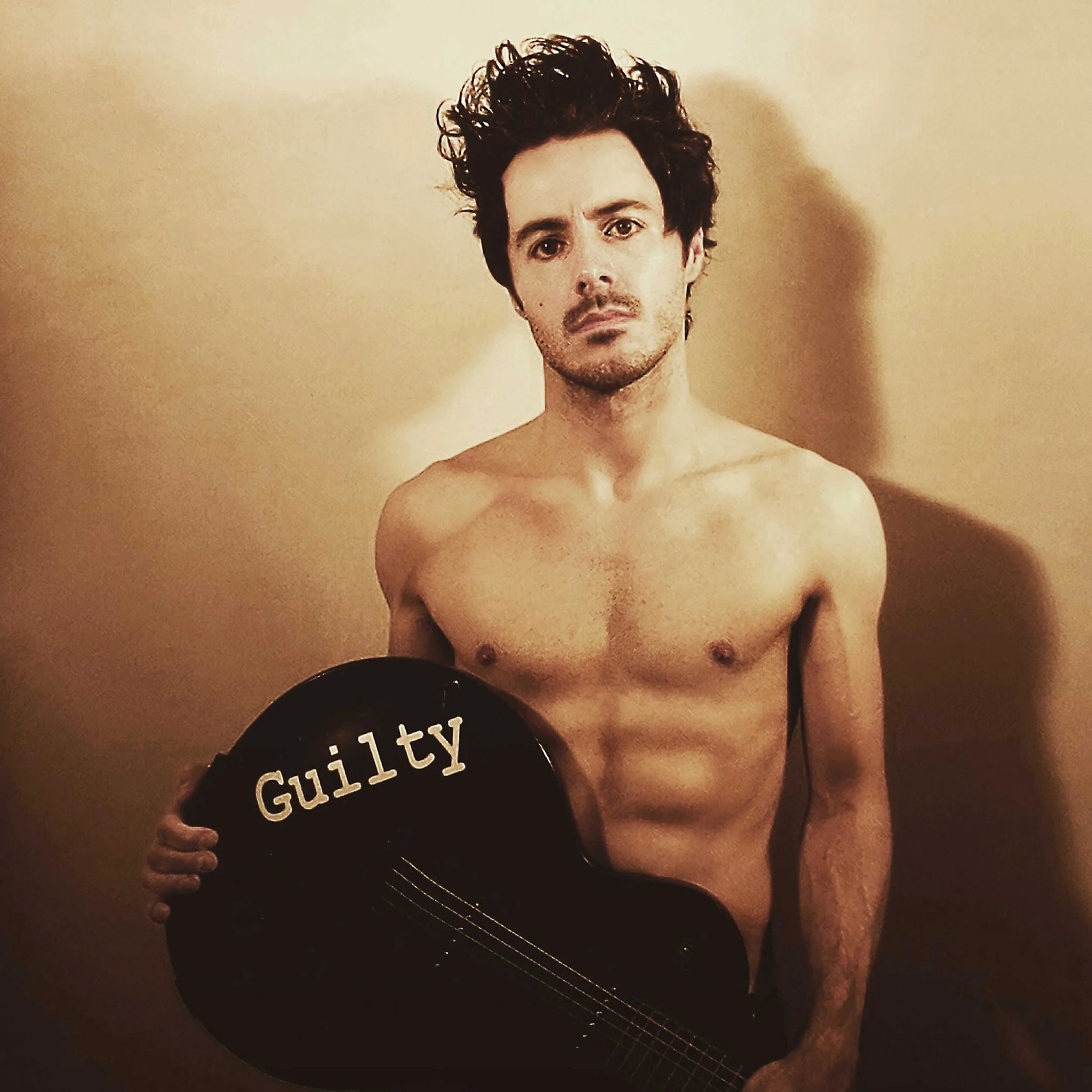 James Kennedy, singer, author and member of the band 'James Kennedy and The Underdogs' posing topless with an electric guitar and spikey hair