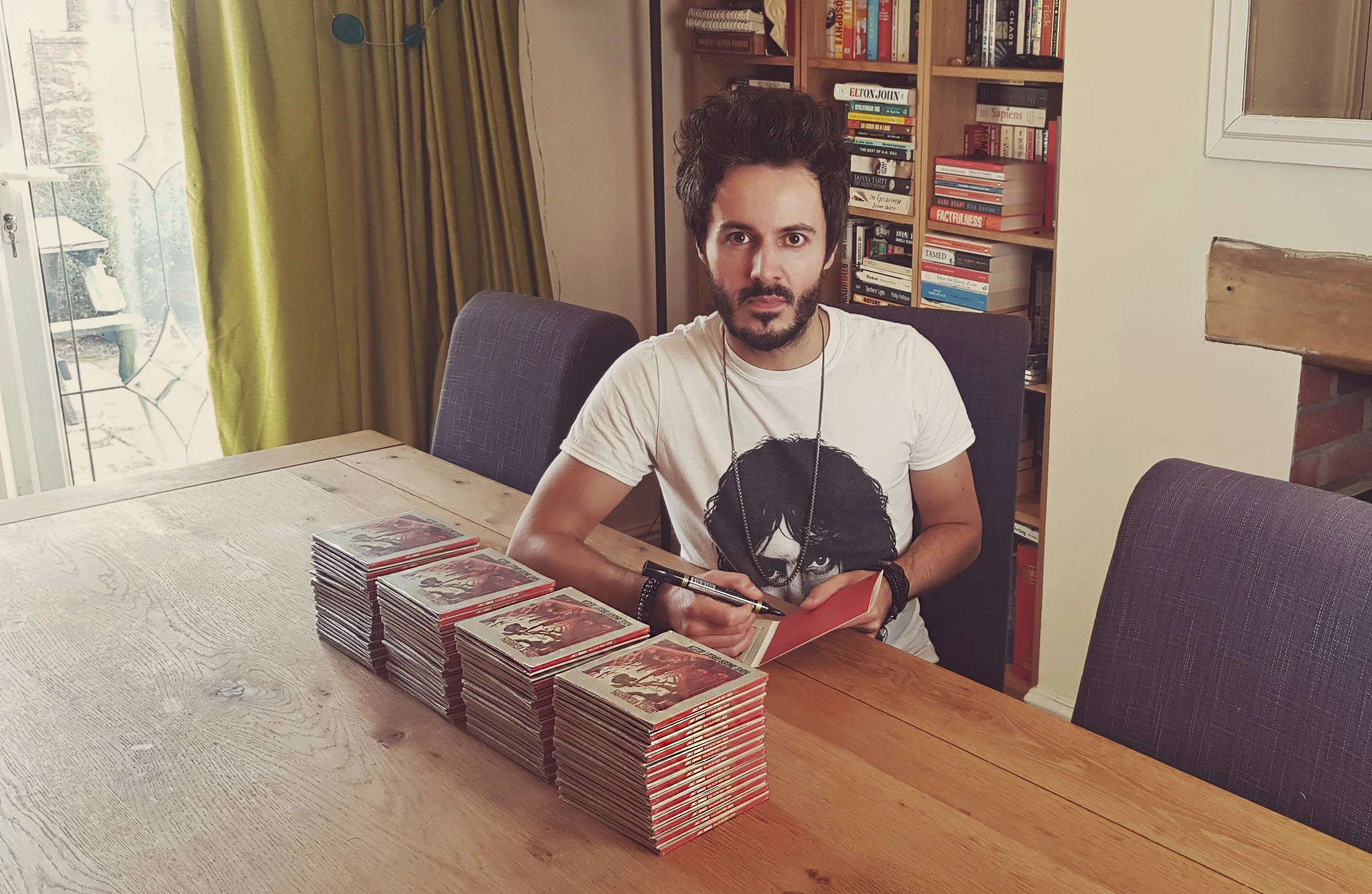 James Kennedy, singer in the rock band James Kennedy and The Underdogs signing a stack of CD's wearing a Frank Zappa T-shirt