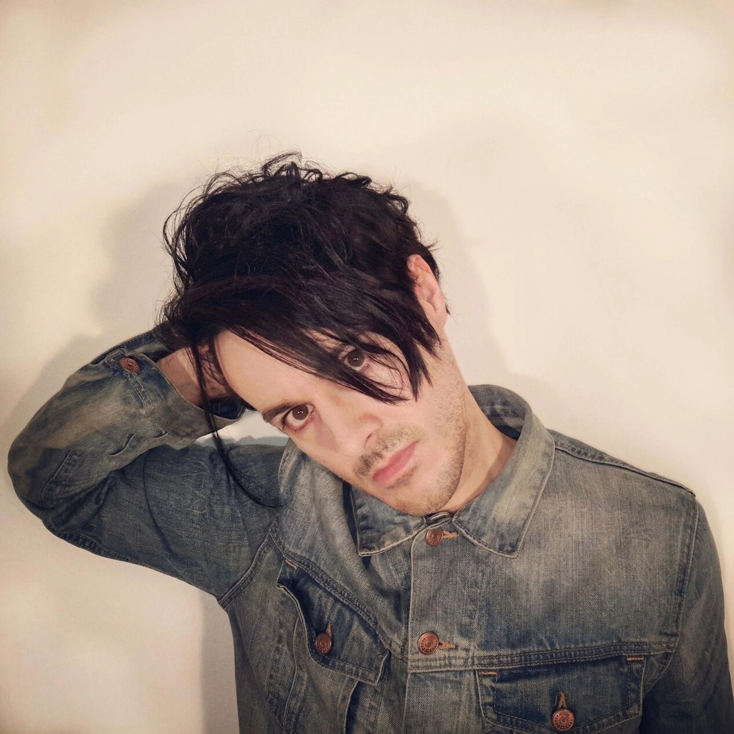 James Kennedy, the singer songwriter from Wales and frontman of the rock band 'Kyshera' posing in a denim jacket and a long fringe