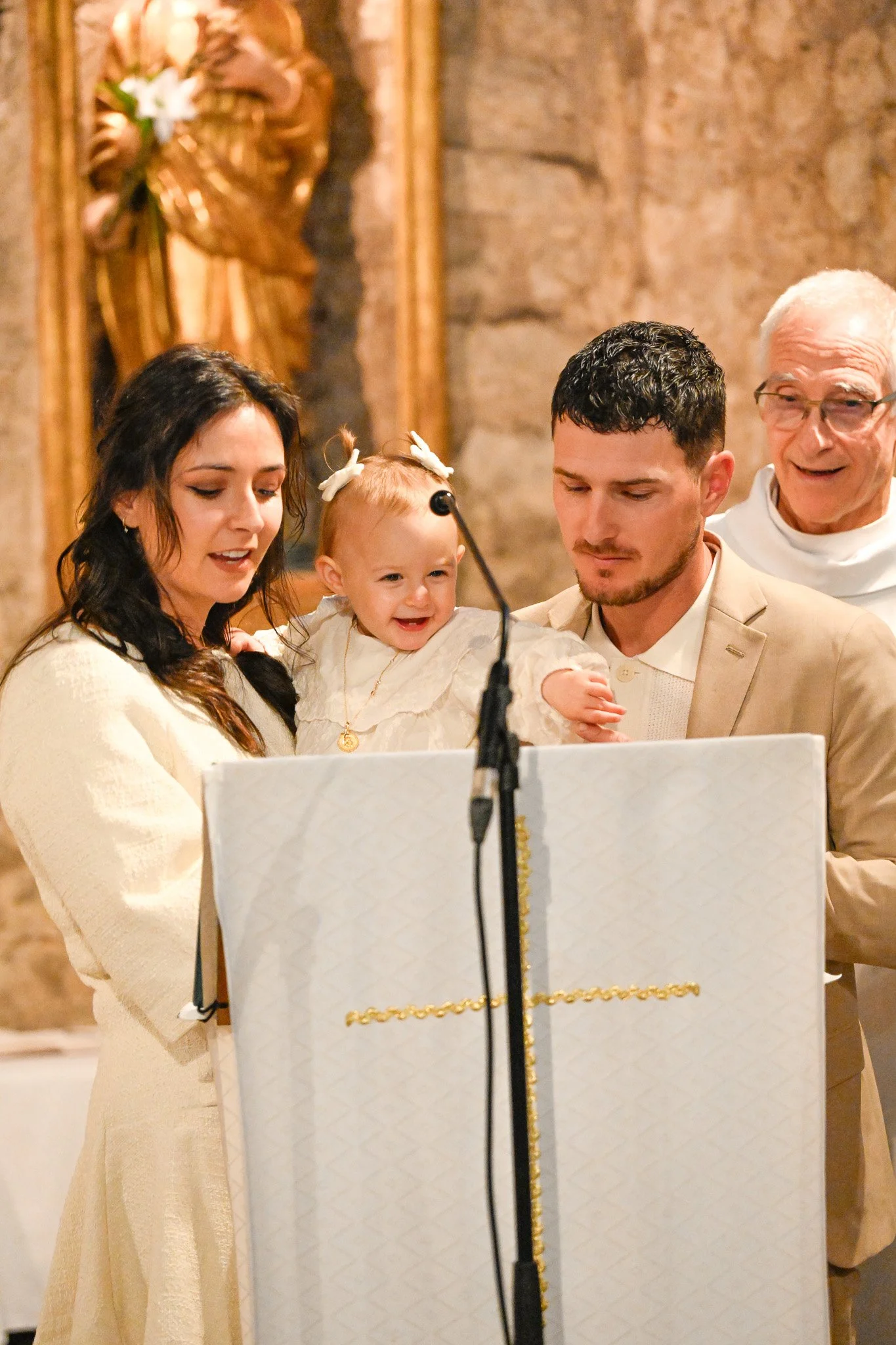 Un groupe de cinq personnes, dont un bébé, participant à une cérémonie religieuse dans une église, avec un autel décoré en arrière-plan.