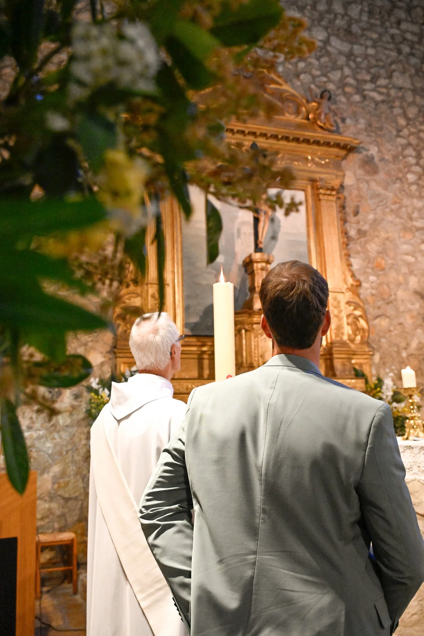 Deux hommes regardent un altar dans une église, avec une grande bougie blanche allumée devant eux.