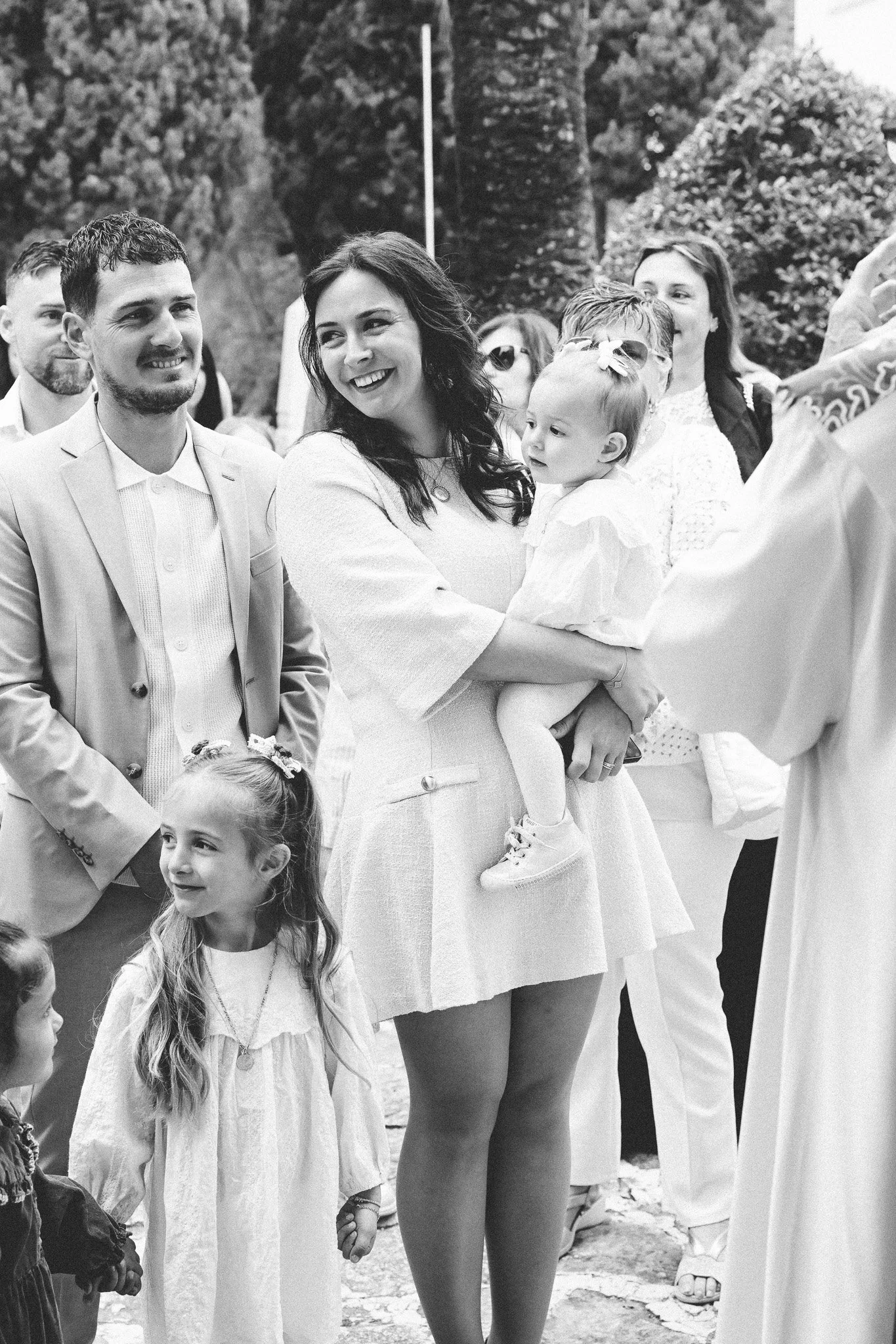 Groupe de personnes, principalement adultes, avec quelques enfants, lors d'une rencontre en plein air, la scène est en noir et blanc.