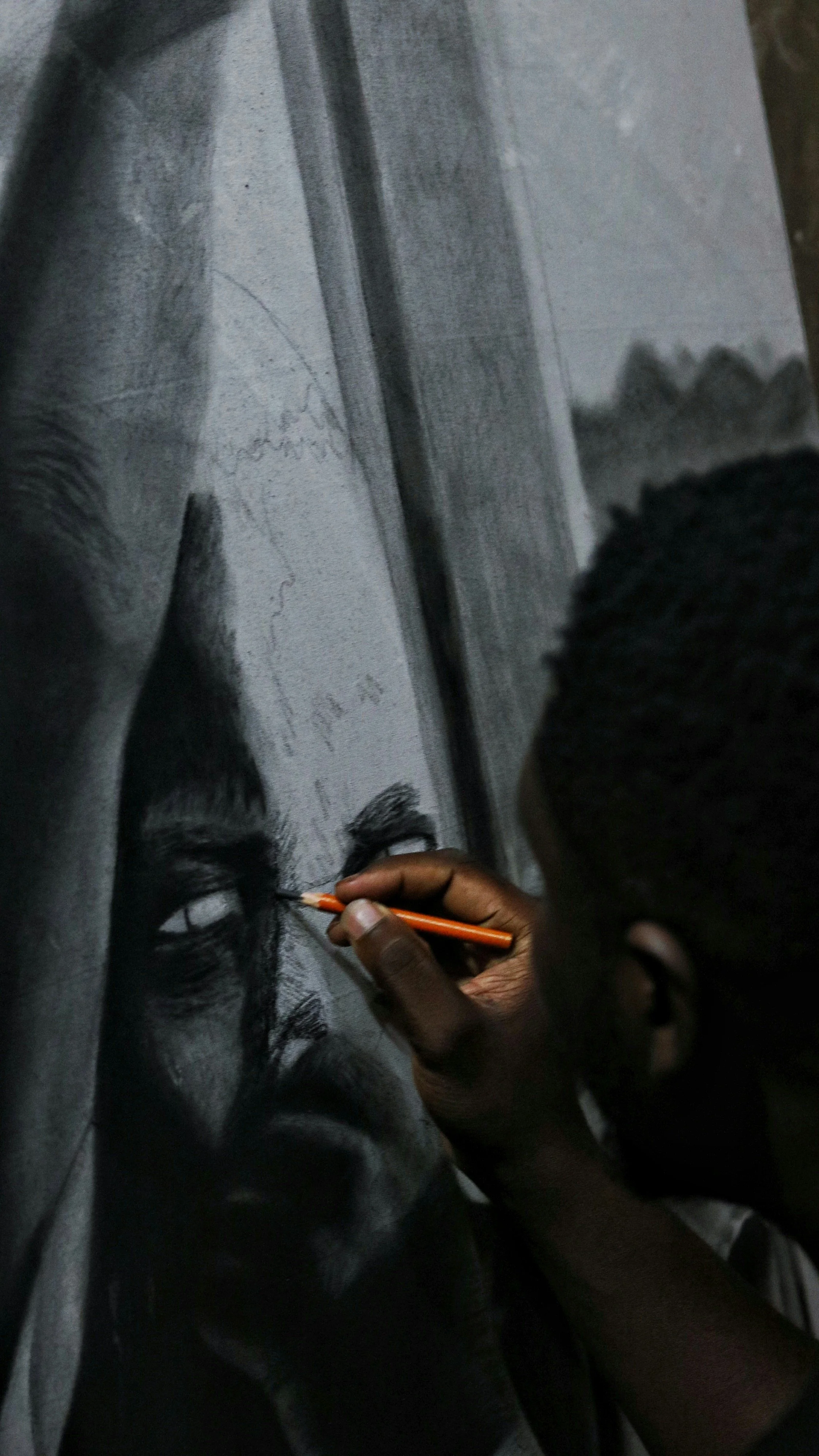 Artist creating realistic charcoal or pencil portrait of a person's face on a large canvas.