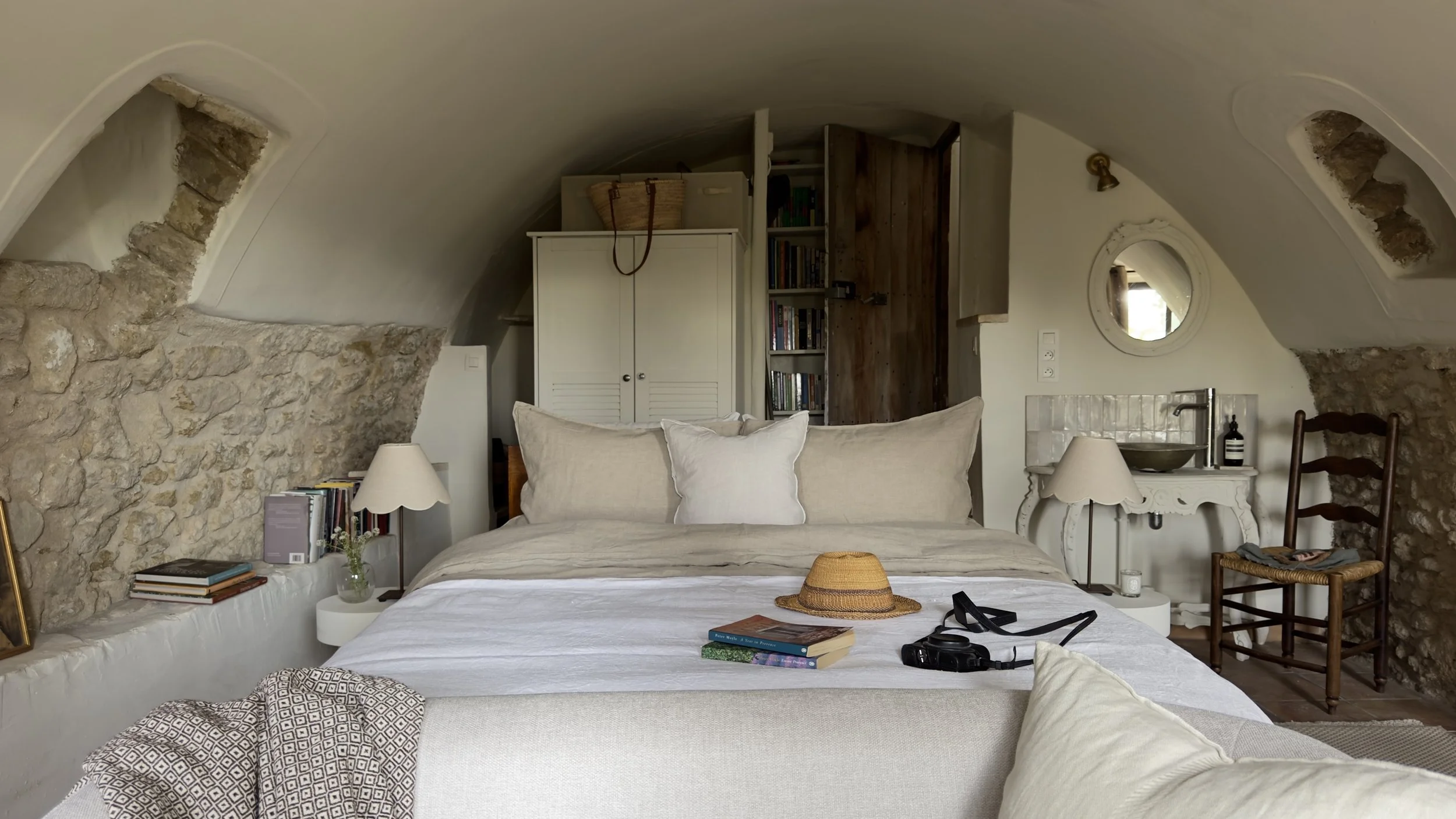 bedroom interior with vaulted ceiling, antique bed linens and a straw hat