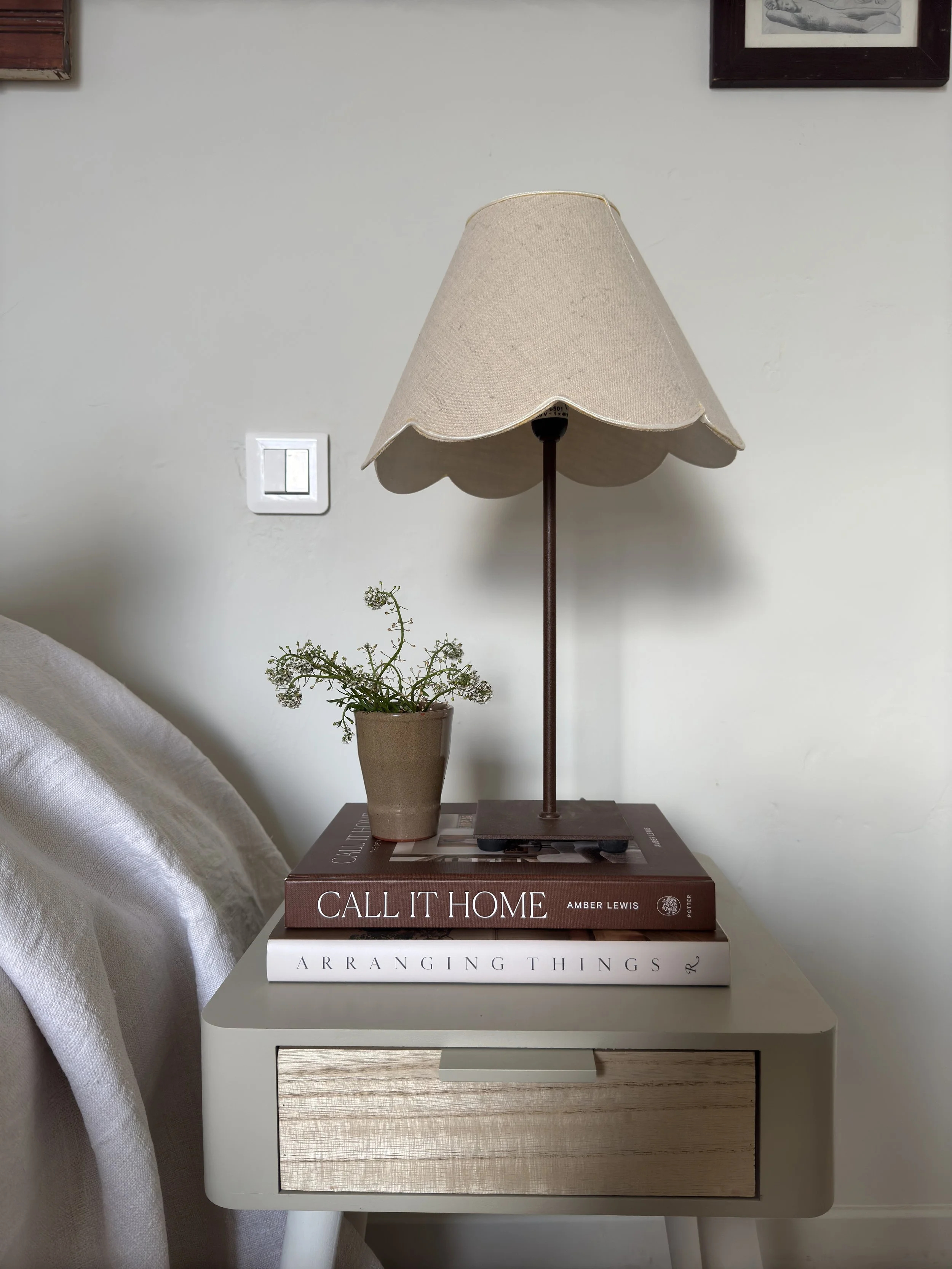 vignette showing a bedside table, scallop edge lamp shade, books
