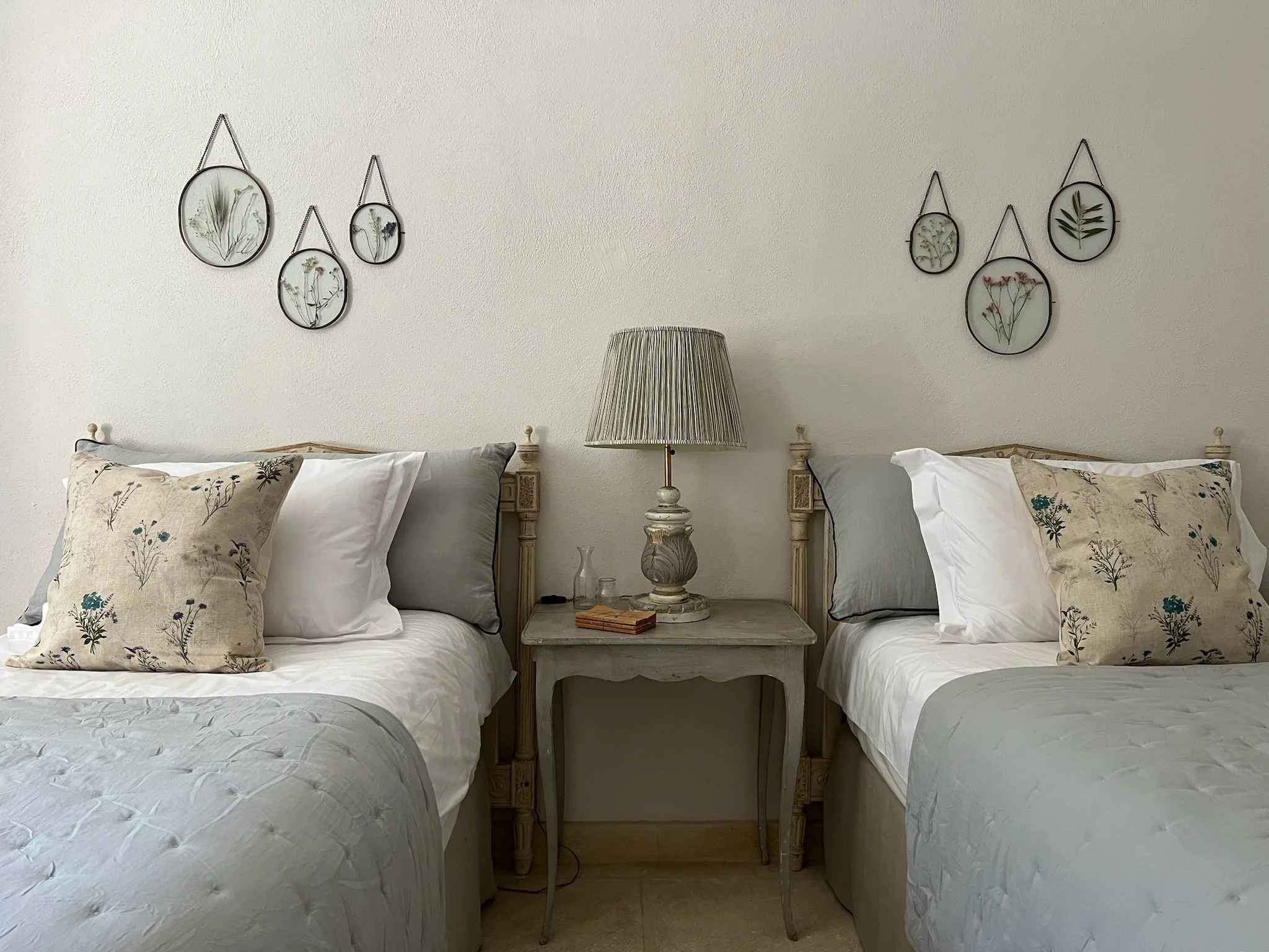 antique beds with a bedside table, lamp and herbiers in oval frames on the wall