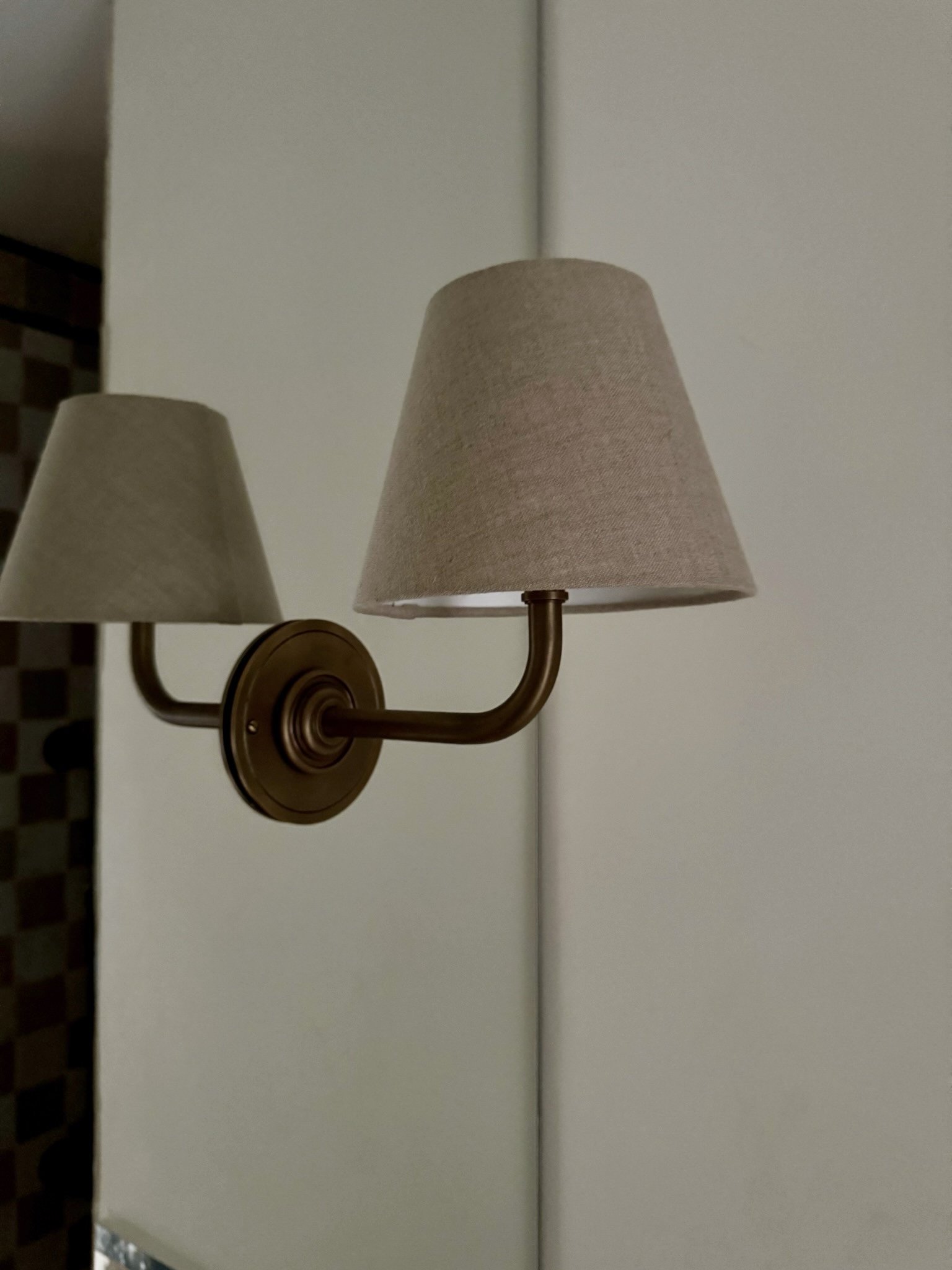 Two wall-mounted lamps with beige fabric shades against a white door.