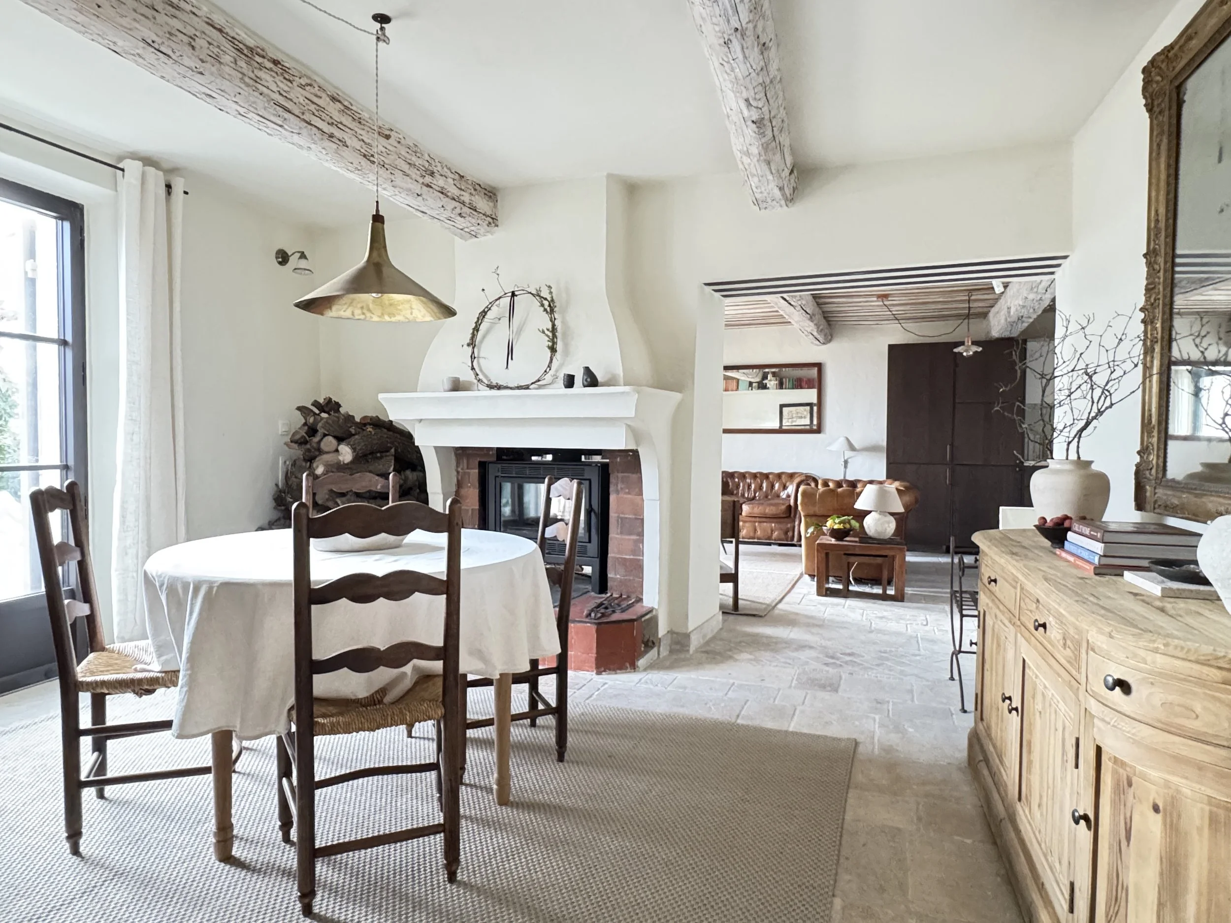 rustic living room interior with fireplace, dining table and provencal chairs