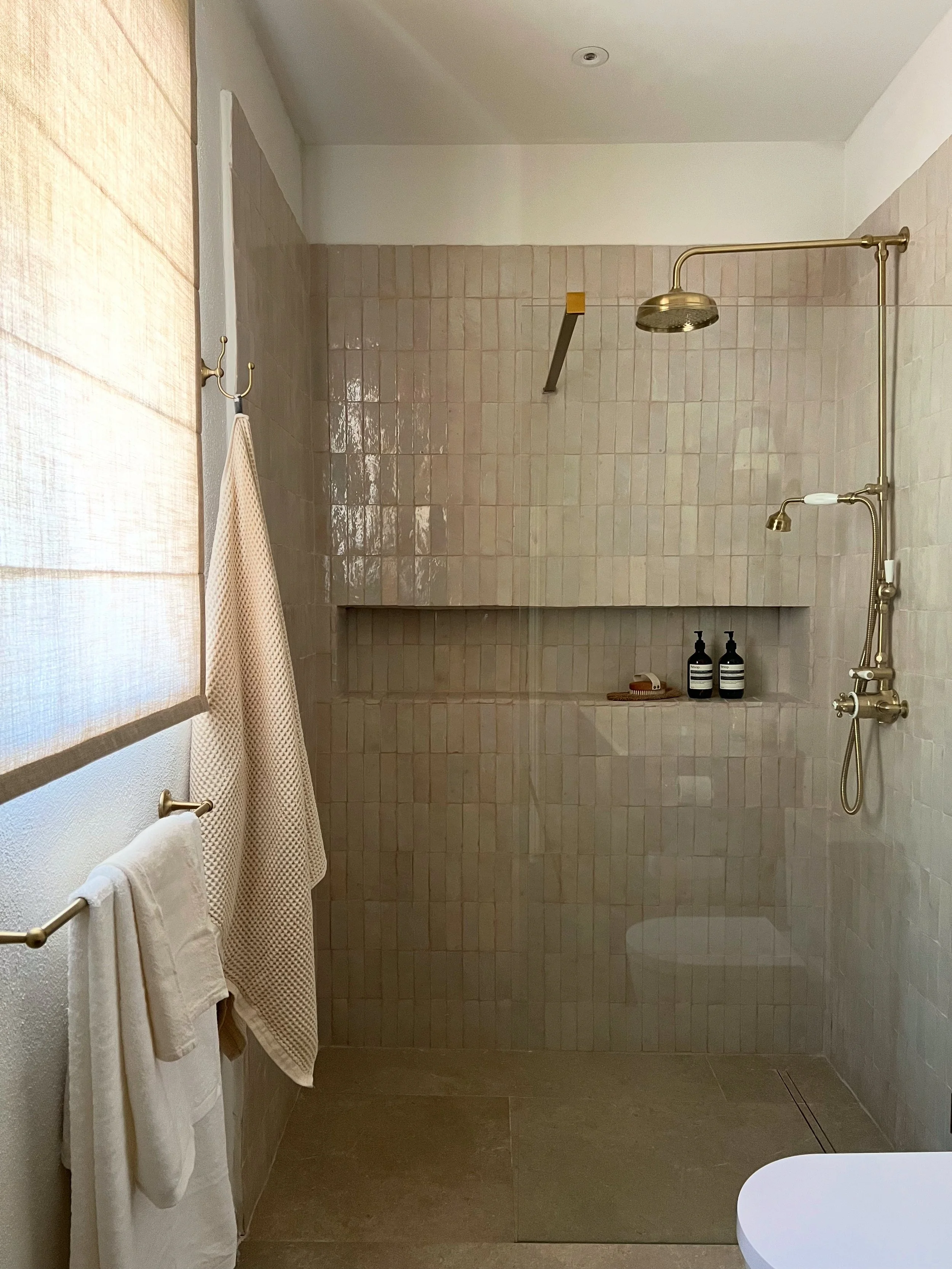 shower with niche tiled in zellige handmade tiles, brass taps and shower, sheer linen blinds, soft white towels, luxury bathroom, wellness