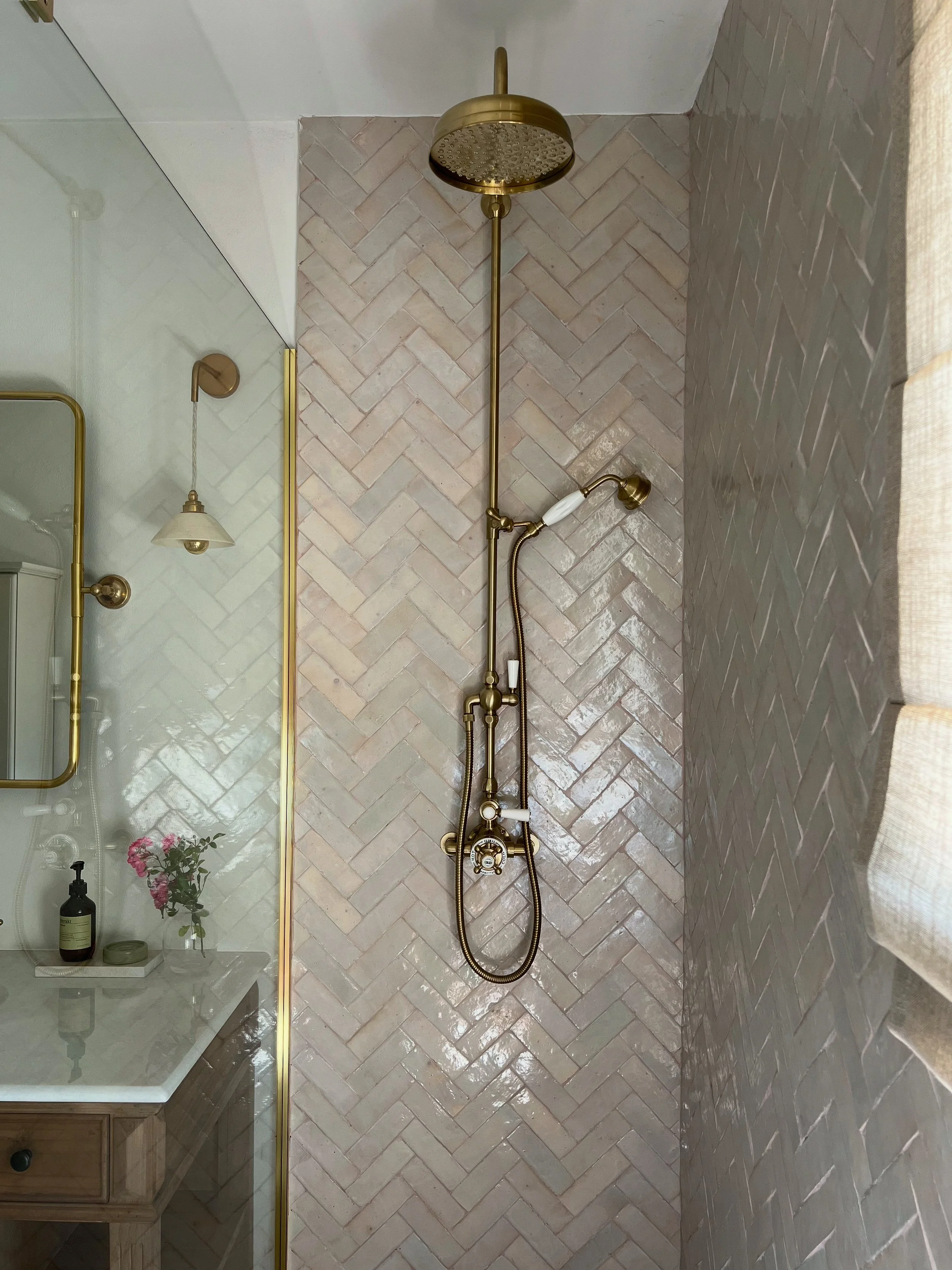 shower tiled in zellige bejmat handmade tiles, herringbone, brass taps and shower, sheer linen blinds, luxury bathroom, wellness, antique vanity, marble, stone, mirror, enamoura lights, light, sun light
