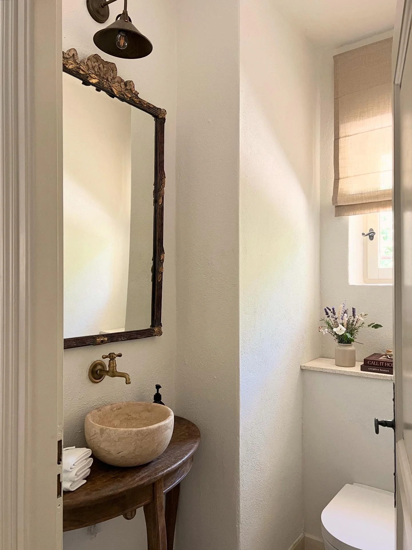 guest toilet, natural wood console with stone basin, antique brass tap, antique mirror, bronze light